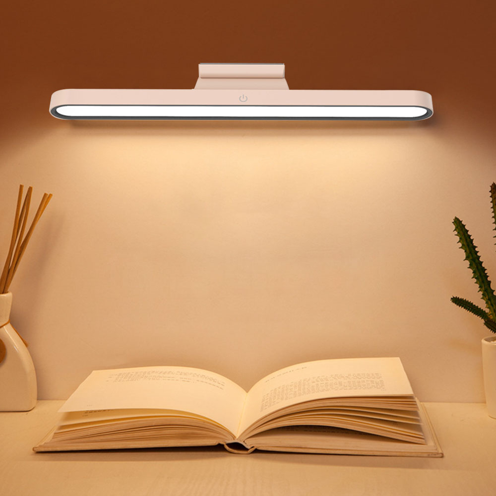 Ein offenes Buch liegt auf einem Tisch, beleuchtet von einer schmalen Lampe.