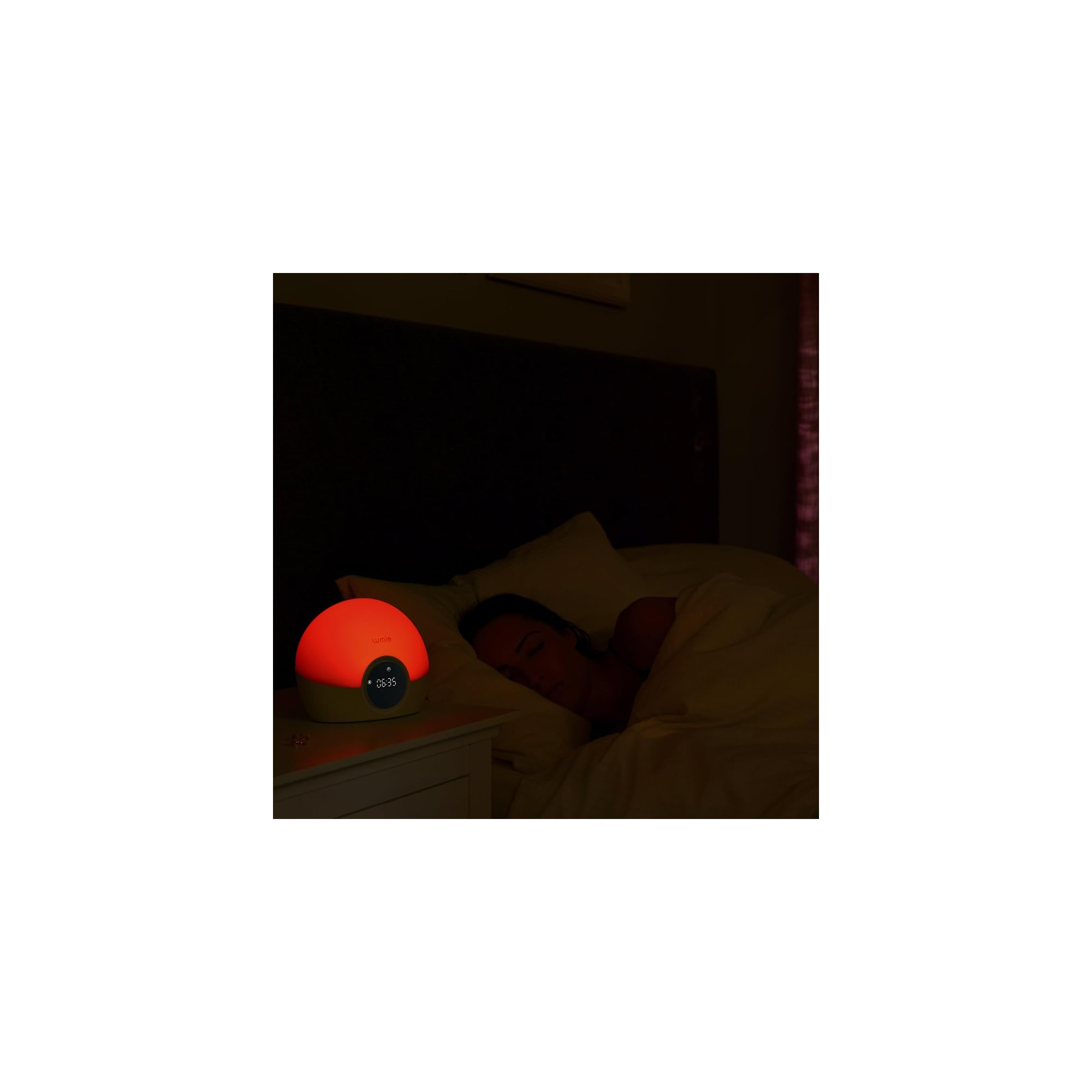Ein roter Wecker leuchtet neben einer schlafenden Person im Bett.