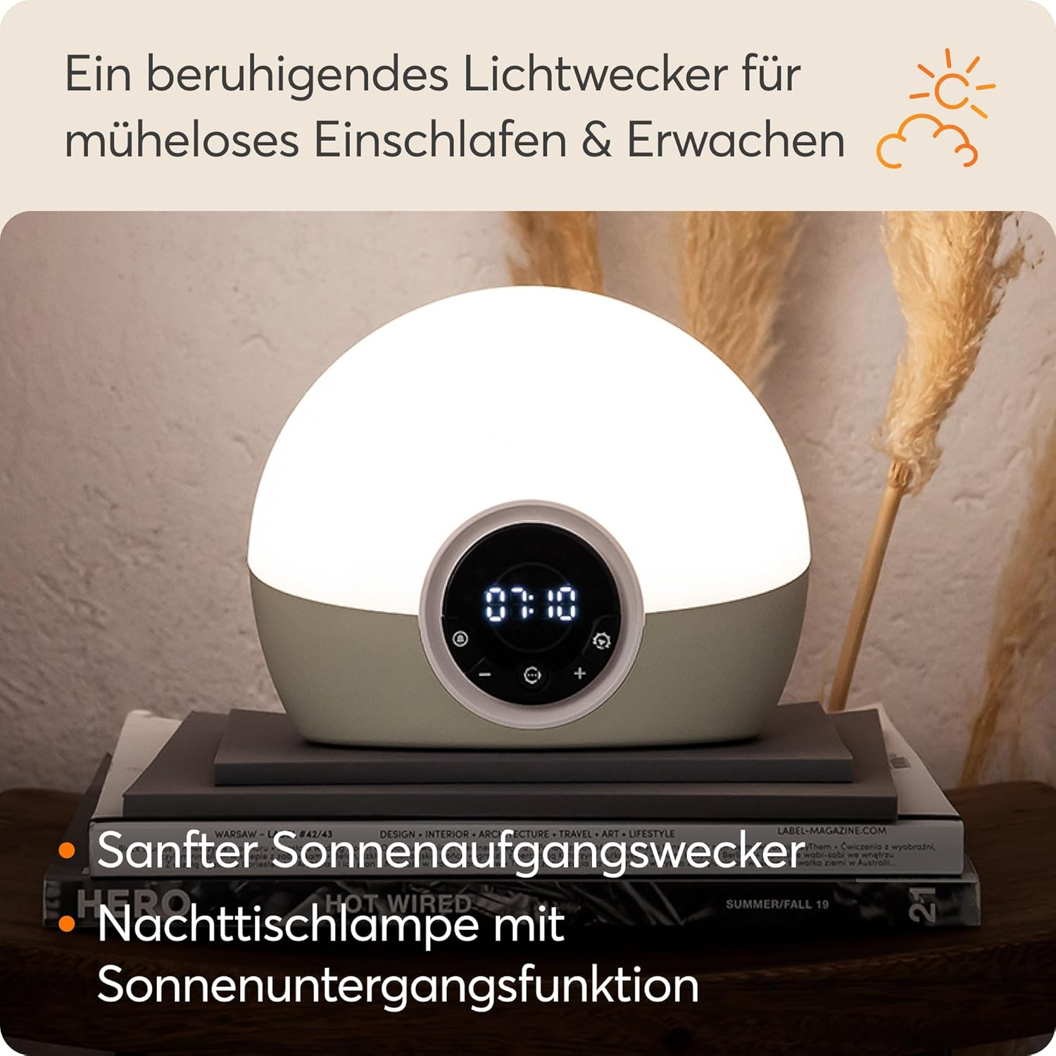 Ein Lichtwecker mit digitaler Anzeige auf Büchern, daneben Dekogräser.