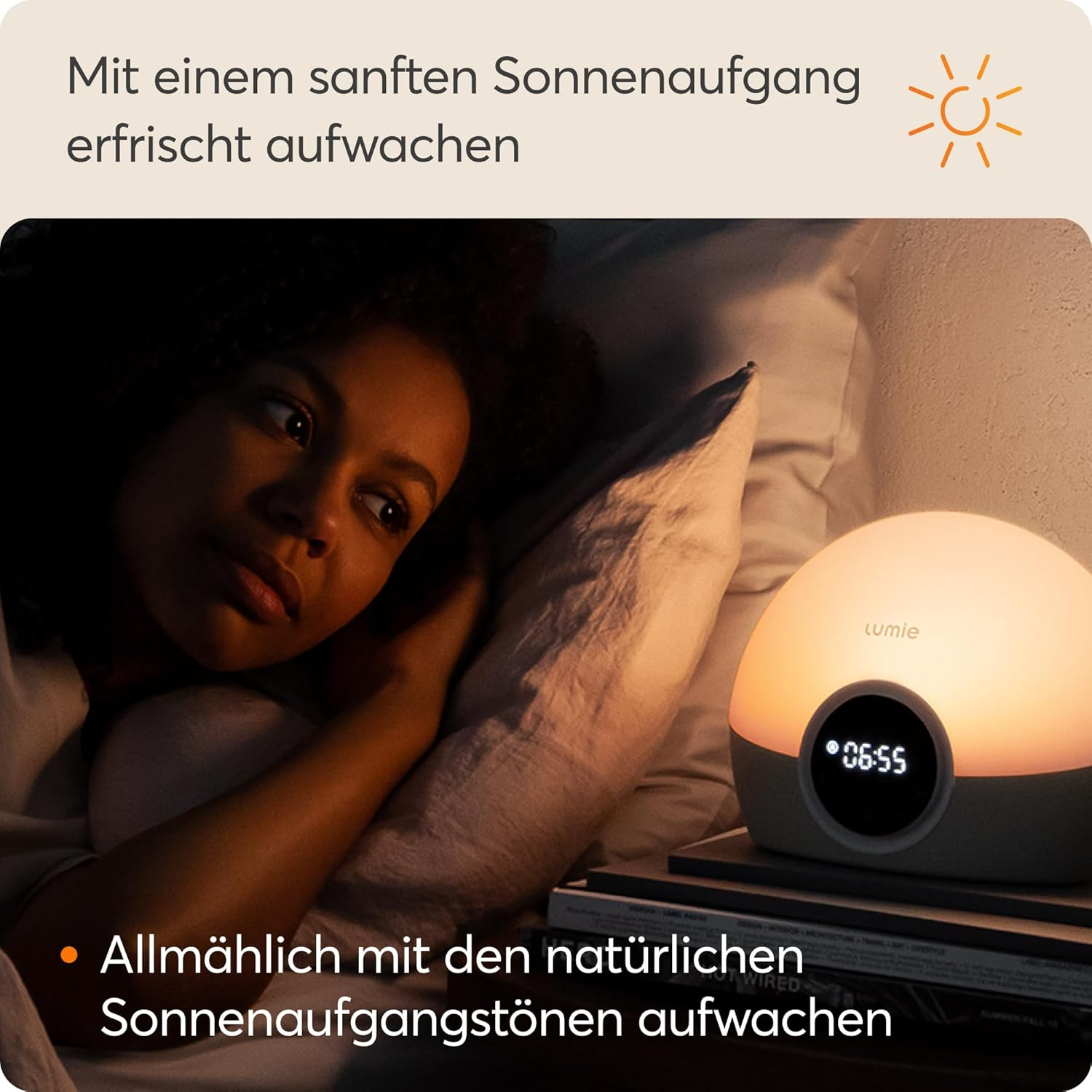 Eine Frau liegt im Bett, neben ihr ein Nachttischlicht, das Sonnenaufgang simuliert.