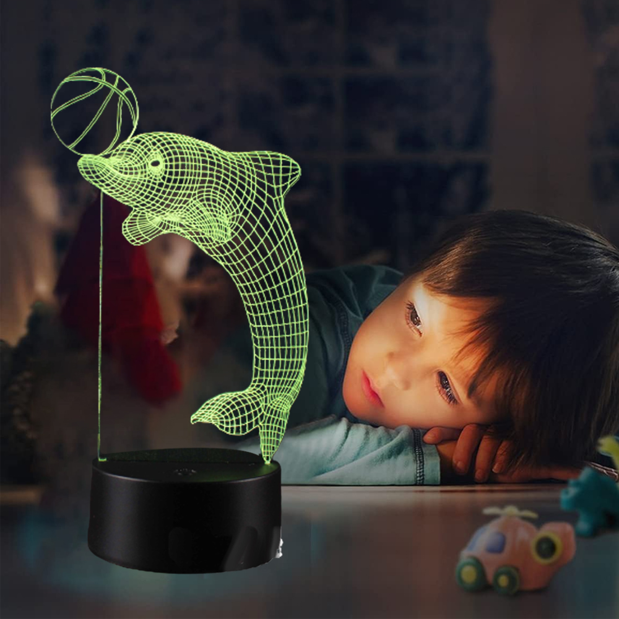 Ein Junge schaut auf eine leuchtende Delfinlampe mit einem Basketball.