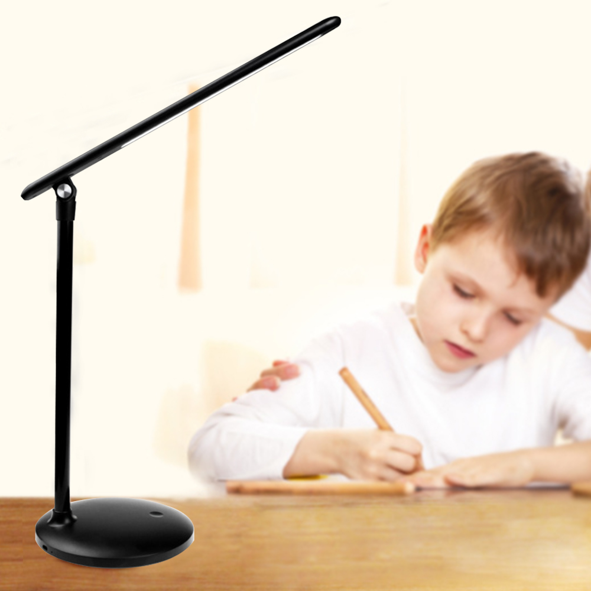 Ein schwarzer Schreibtischlampe steht links, ein Junge schreibt rechts am Tisch.