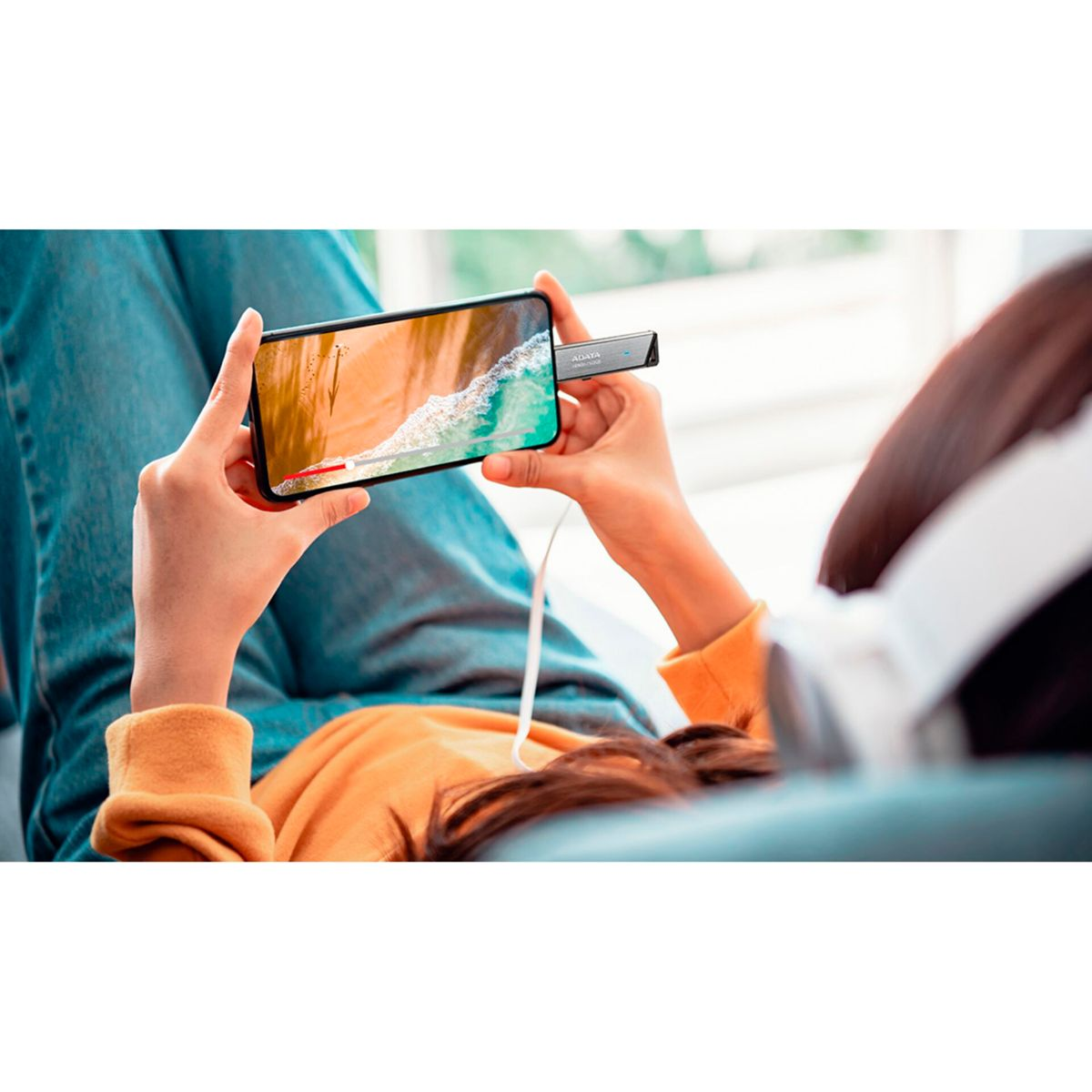 Person hält Handy mit Strandvideo, verbunden mit ADATA-Laufwerk.