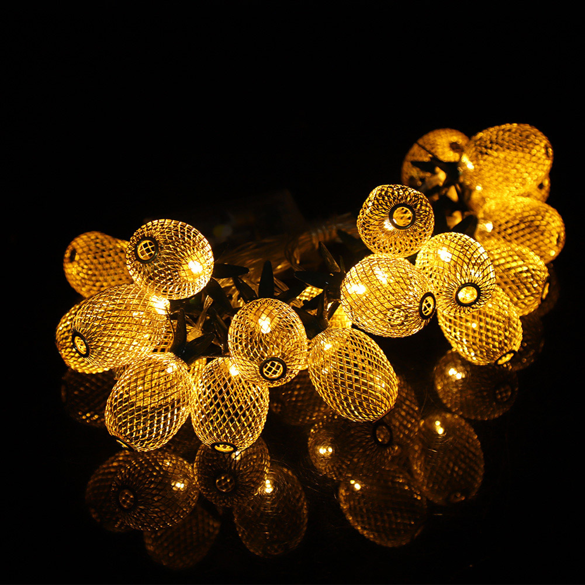 Goldene Lichterkettenkugeln mit Gittermuster auf schwarzem Hintergrund.