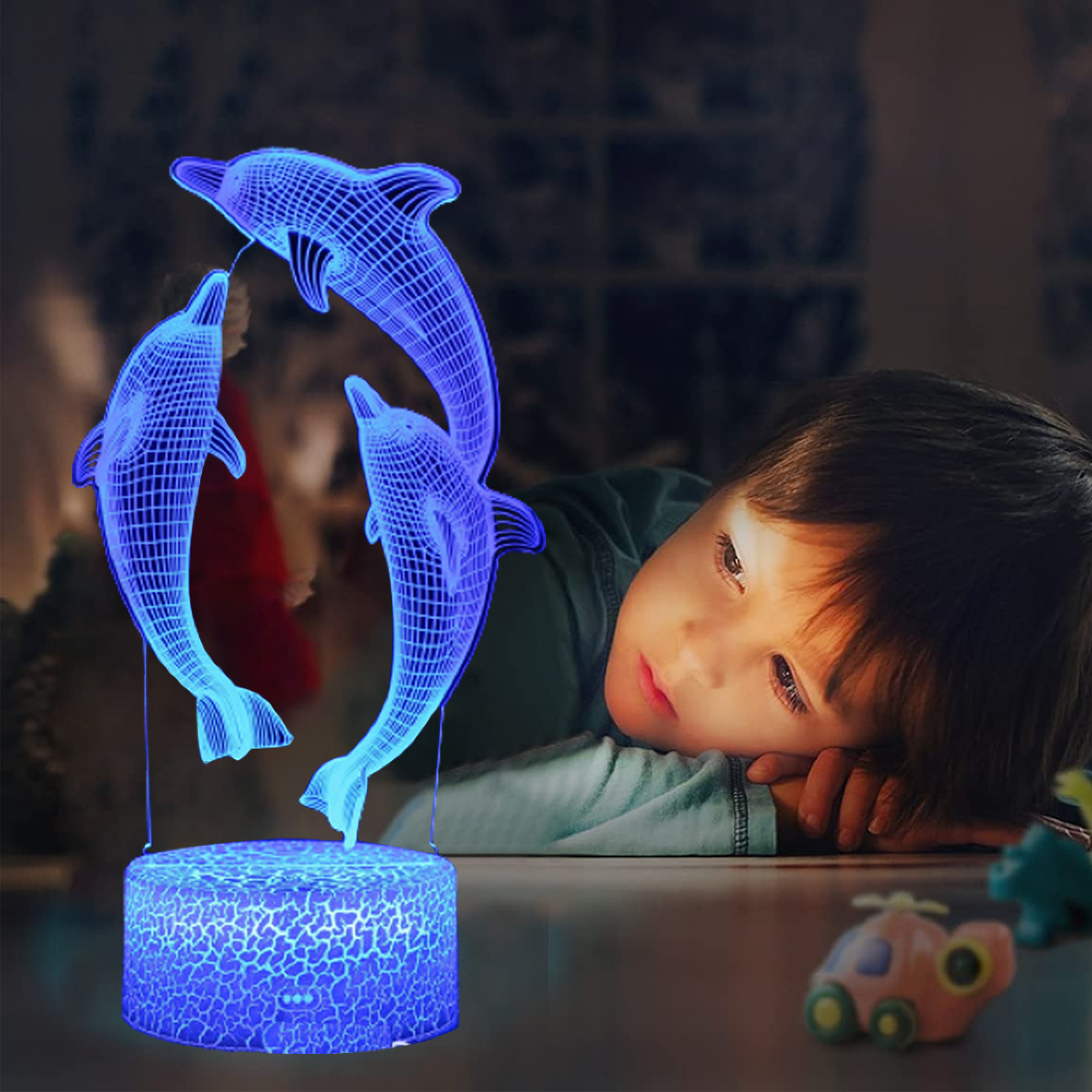 Ein Junge liegt auf dem Bauch und schaut auf eine blaue 3D-Delfinlampe.