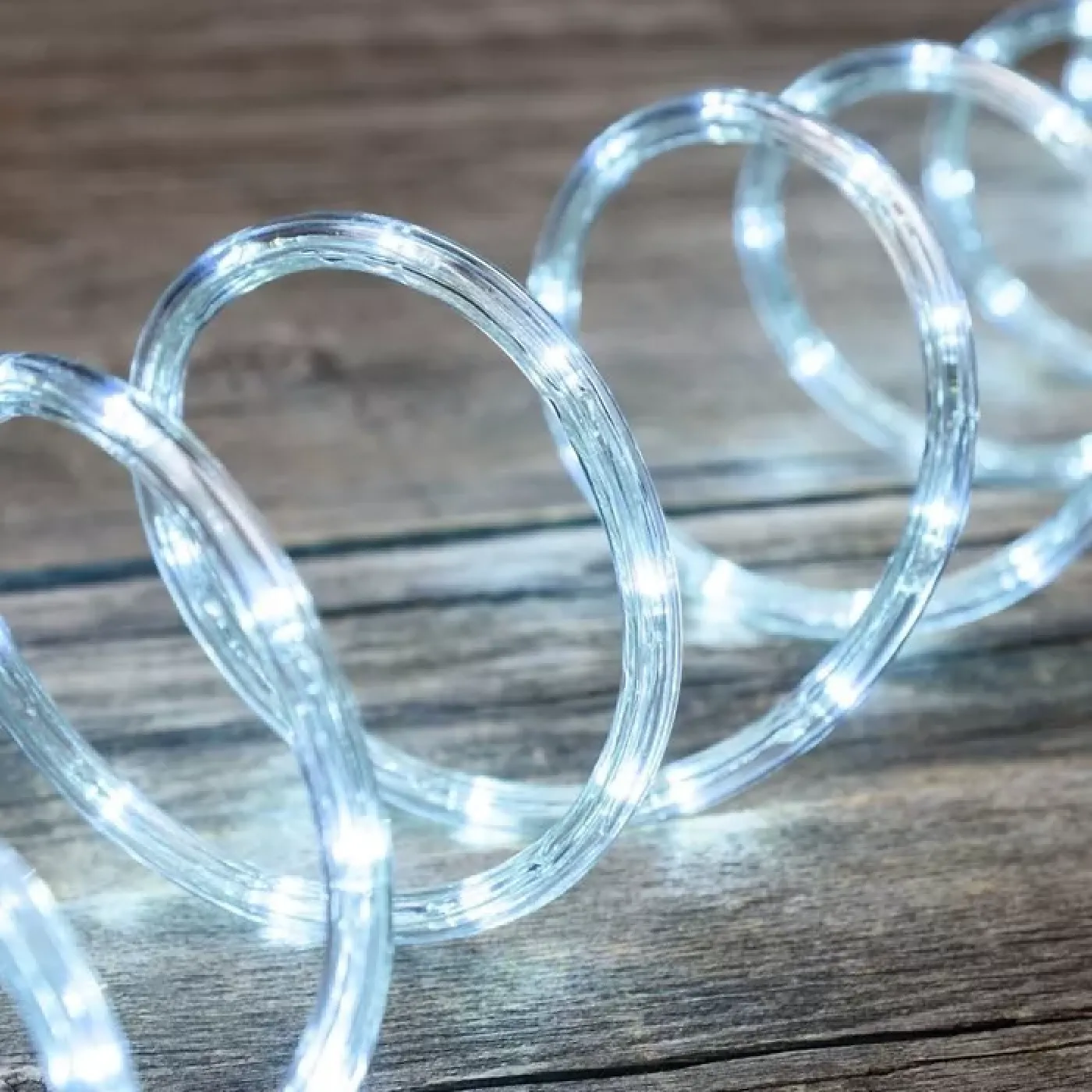 Eine aufgewickelte Schnur mit weißen LED-Lichtern auf Holz.