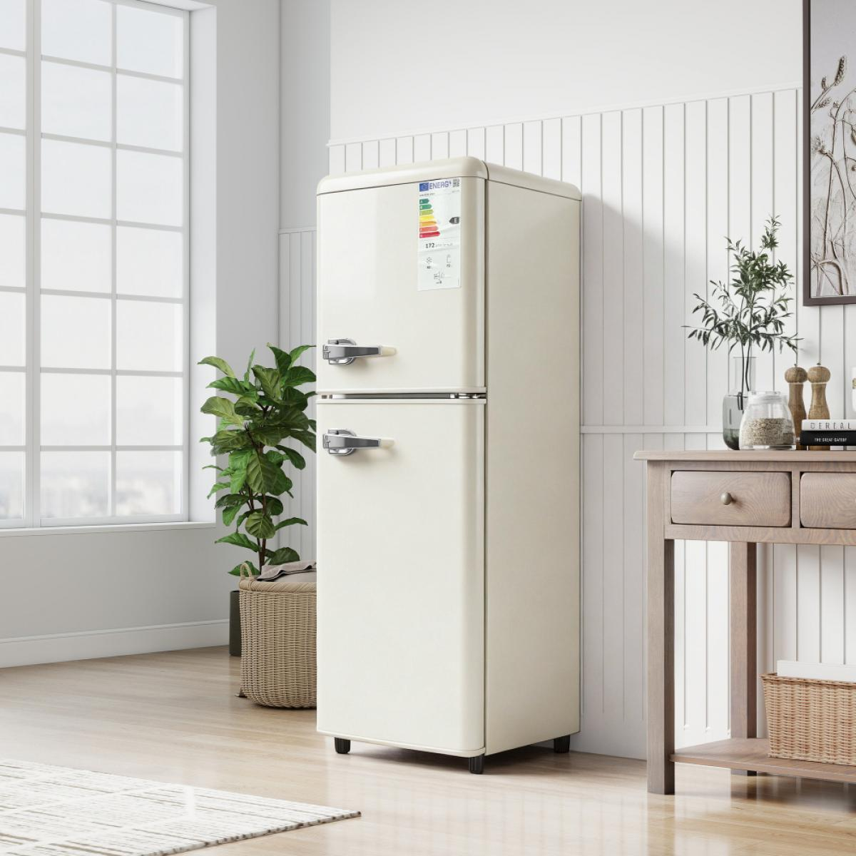 Ein cremefarbener Retro-Kühlschrank steht in einem hellen Raum mit Fenster und Pflanze.