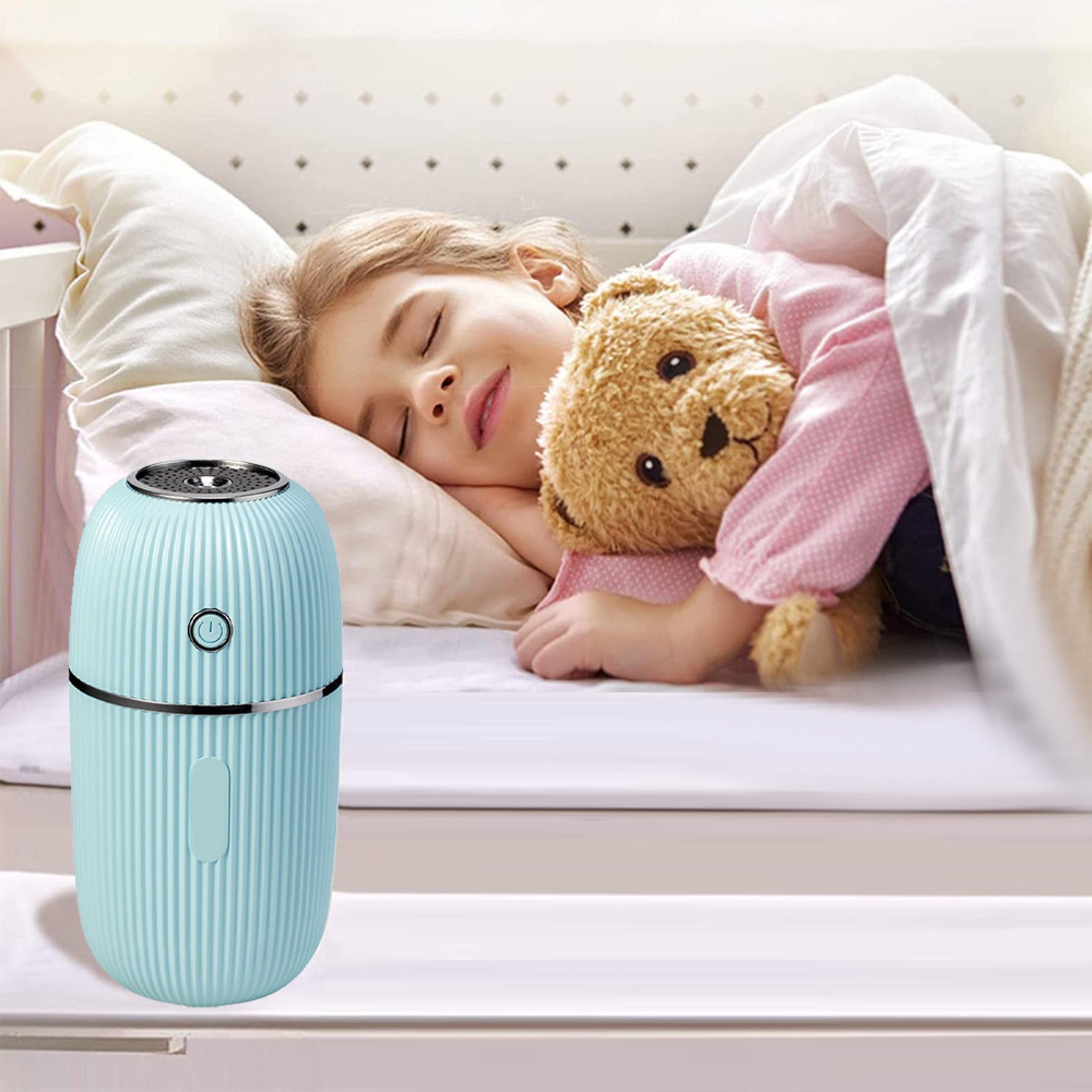 Ein kleines blaues Diffusor neben einem schlafenden Kind und Teddybär.