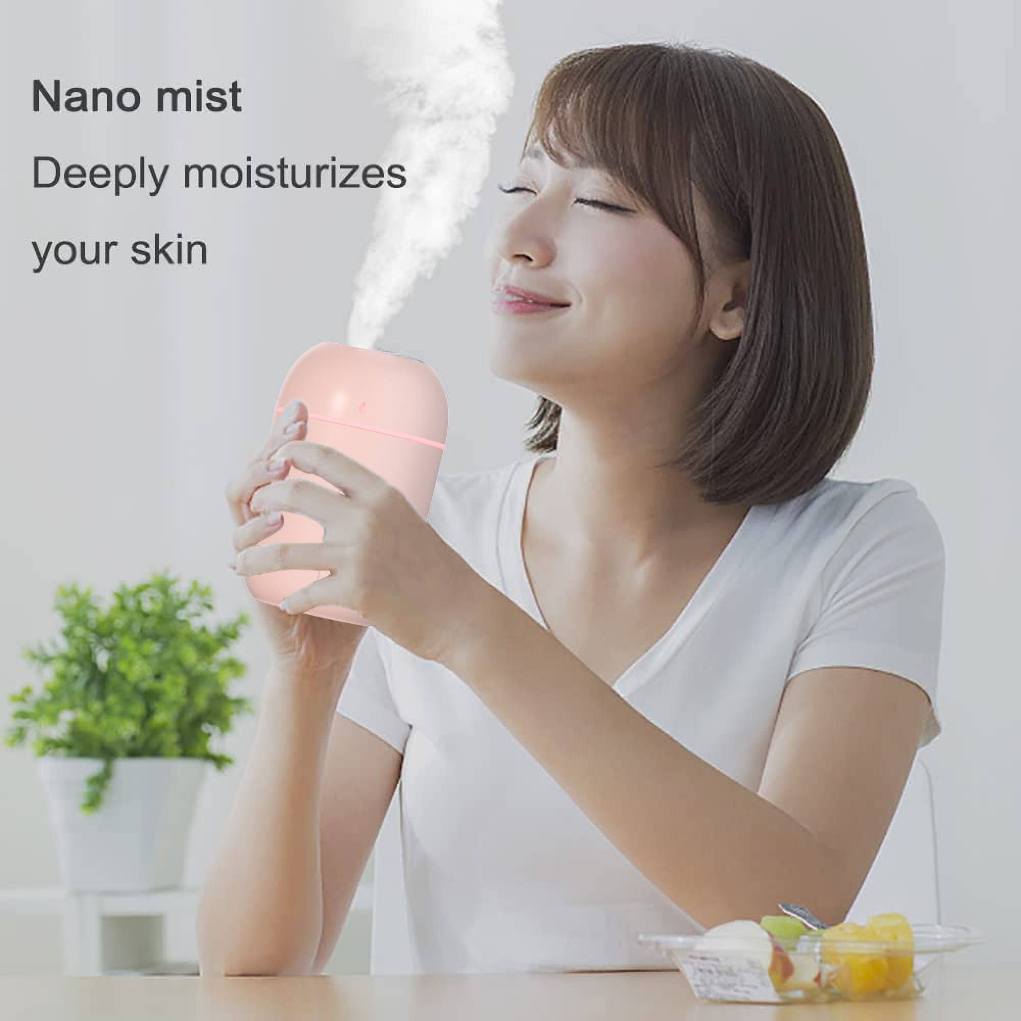 Eine Frau genießt den Nebel eines rosa Luftbefeuchters, der auf einem Tisch steht.