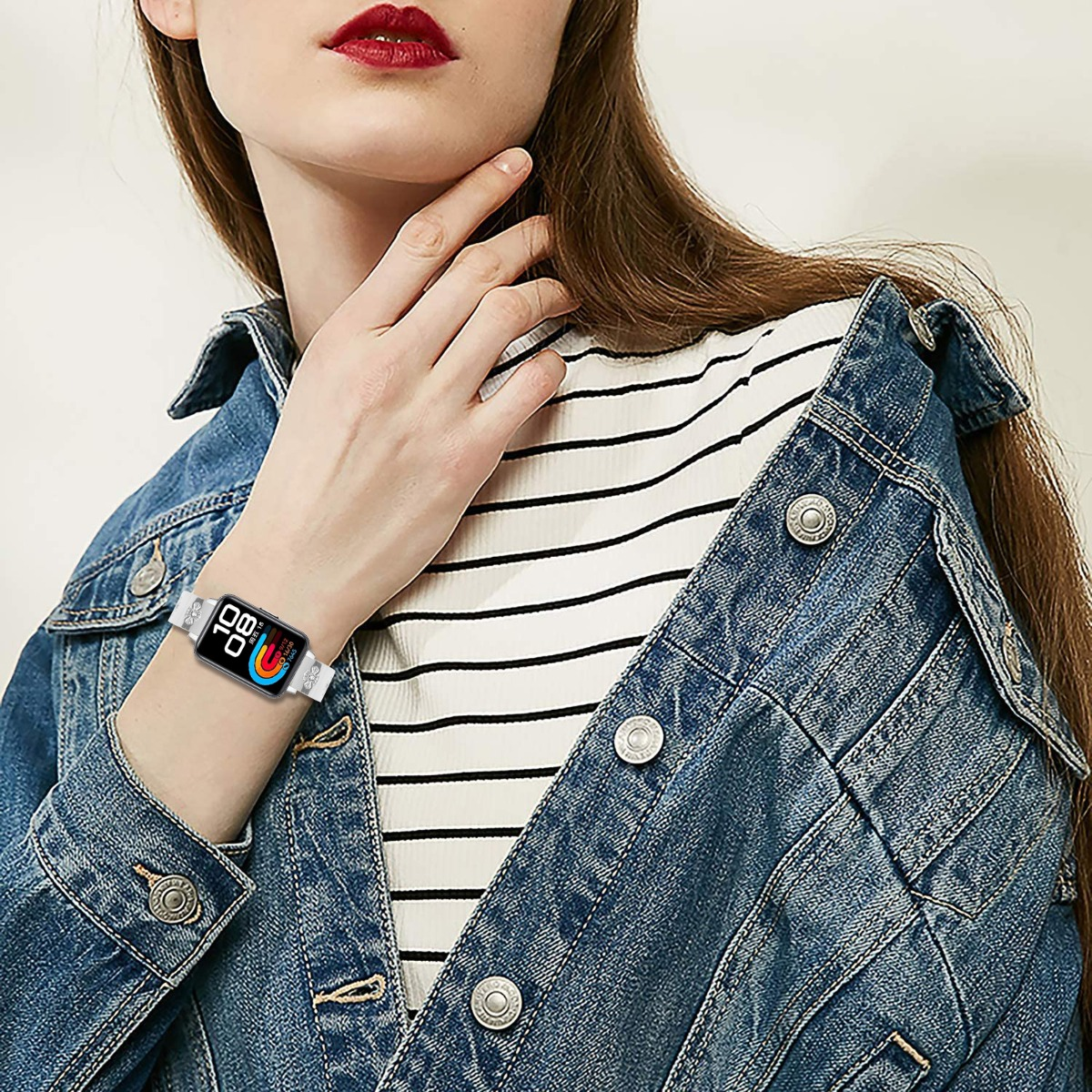 Frau mit Jeansjacke, gestreiftem Hemd und Smartwatch mit bunter Anzeige.