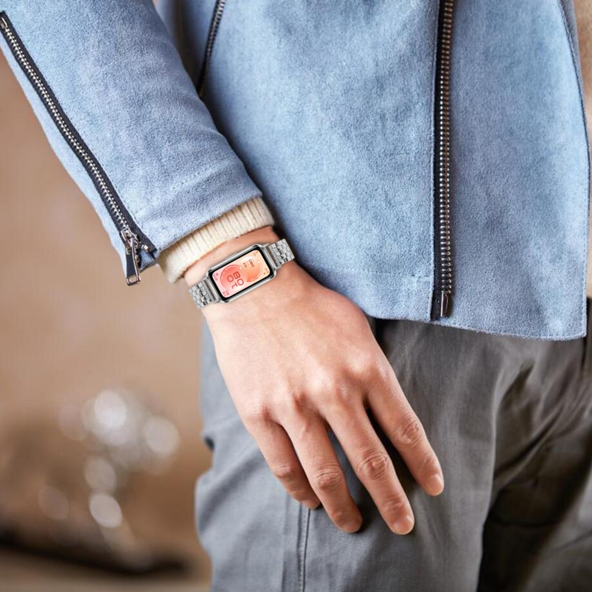 Ein Mann trägt eine blaue Jacke und eine Smartwatch am linken Handgelenk.