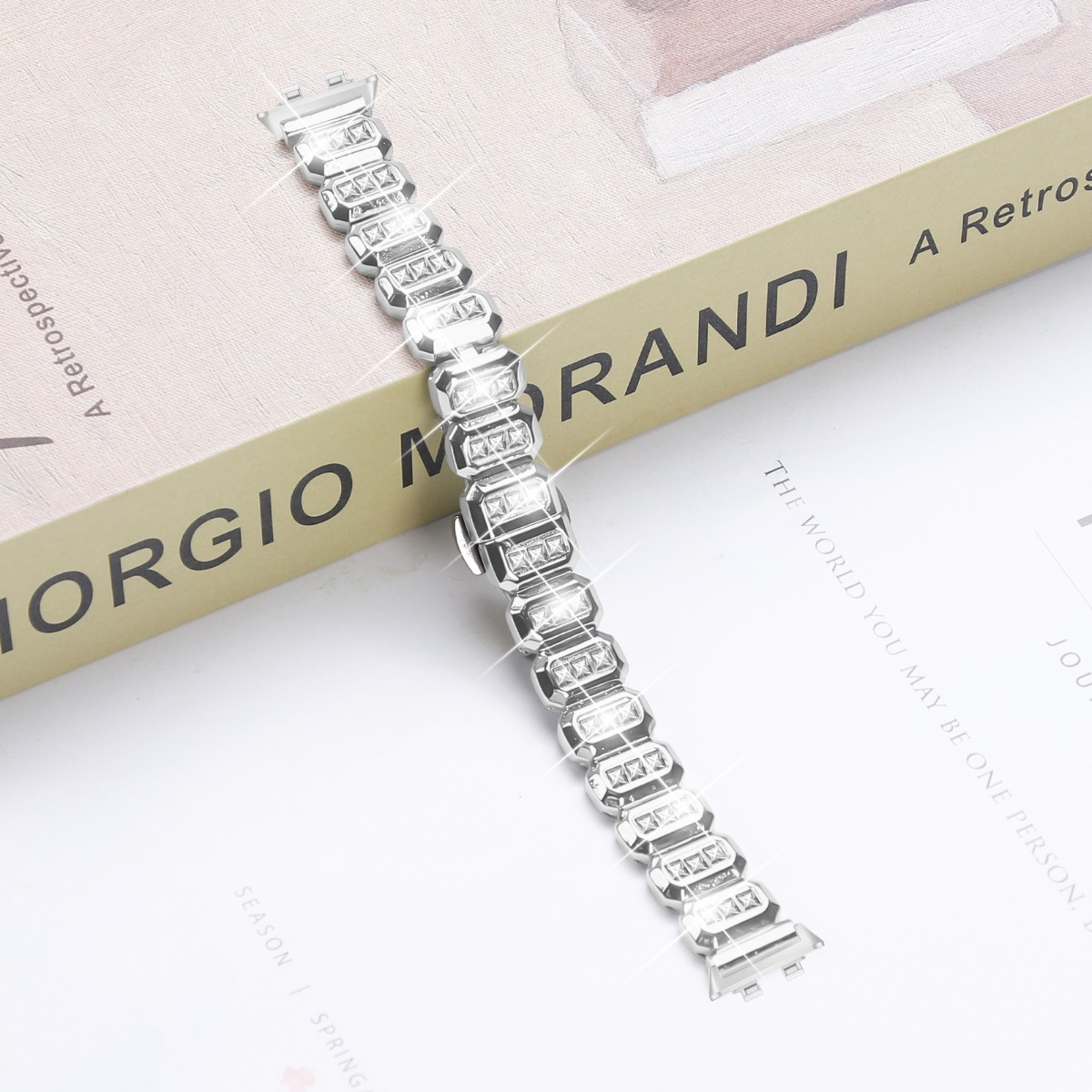 Un cinturino d'argento con gemme trasparenti si trova su un libro con testo.