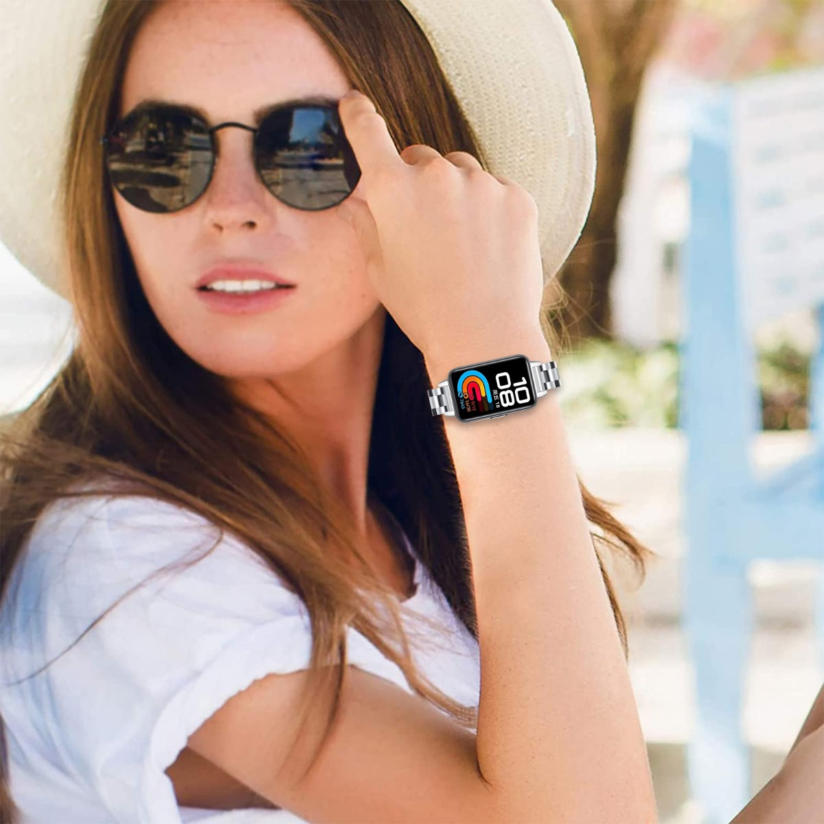 Frau mit Hut und Sonnenbrille trägt eine Smartwatch am Handgelenk.