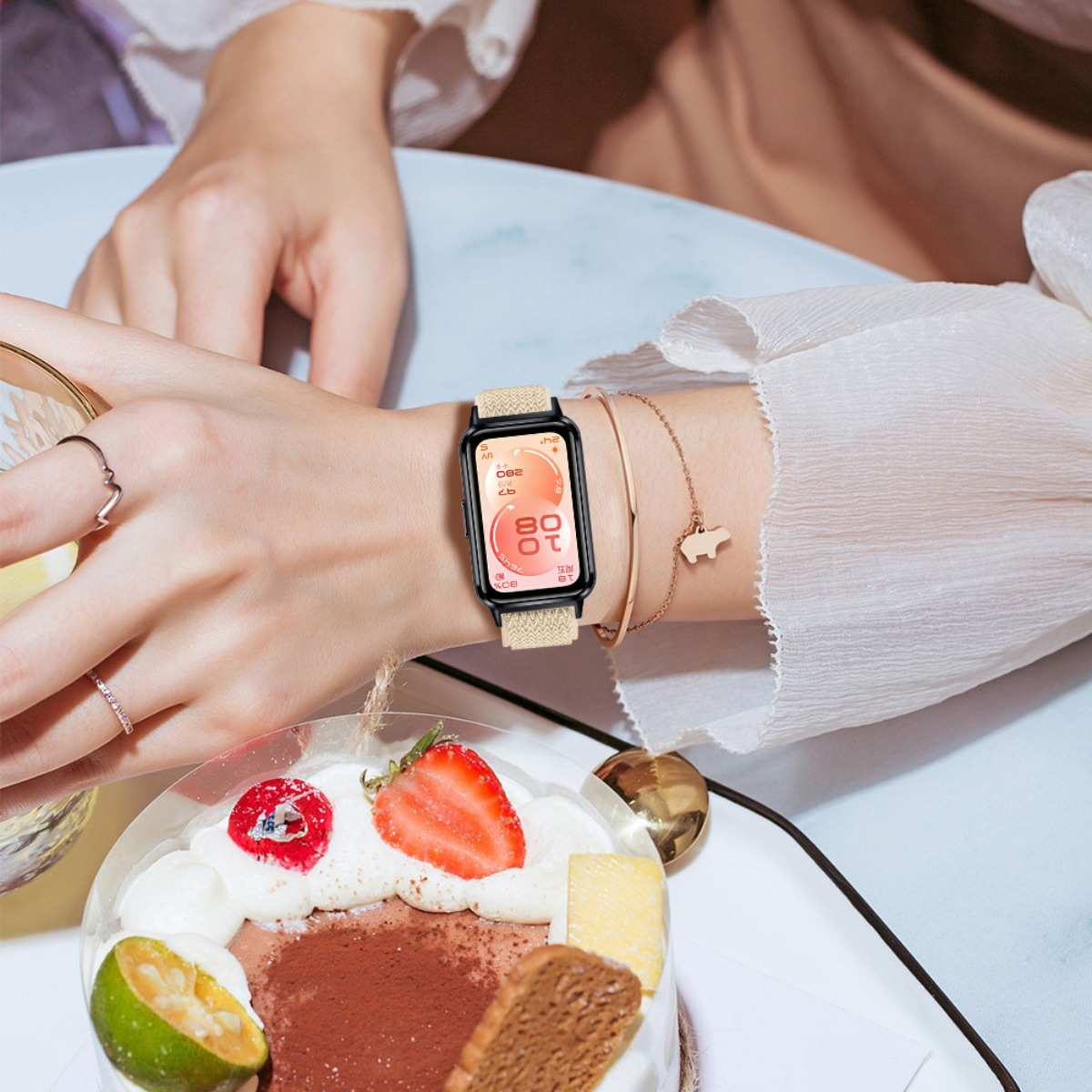 Eine Frau trägt eine Uhr mit hellem Band und eine Halskette mit einem Schweinchenanhänger.