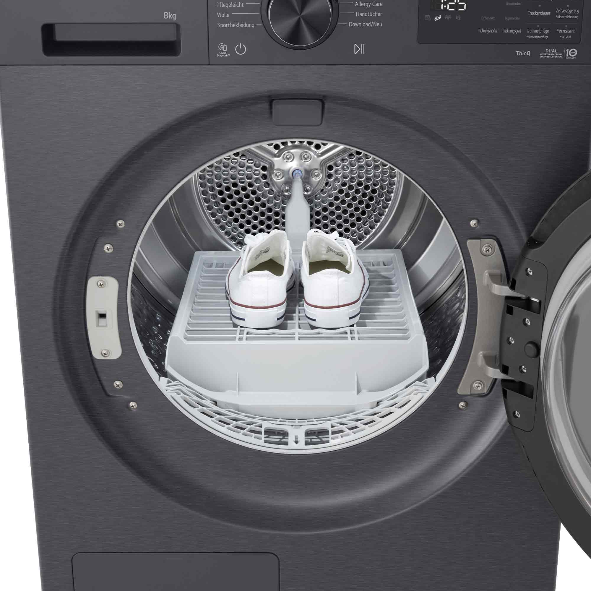 Zwei weiße Turnschuhe stehen auf einem Trockengestell in einer grauen Waschmaschine.