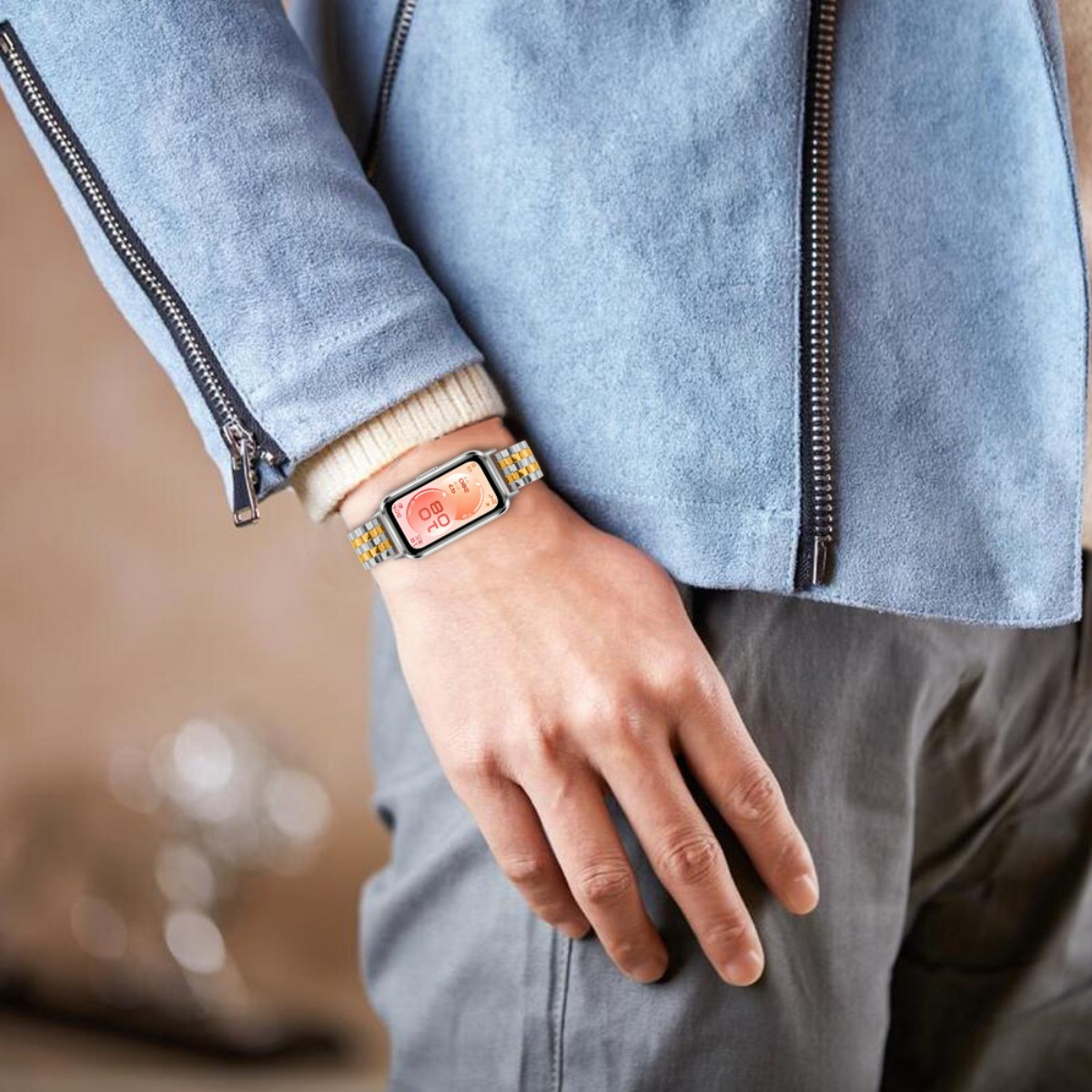 Eine Person trägt eine blaue Jacke, ein weißes Hemd und eine Smartwatch mit silbernem und goldenem Armband.