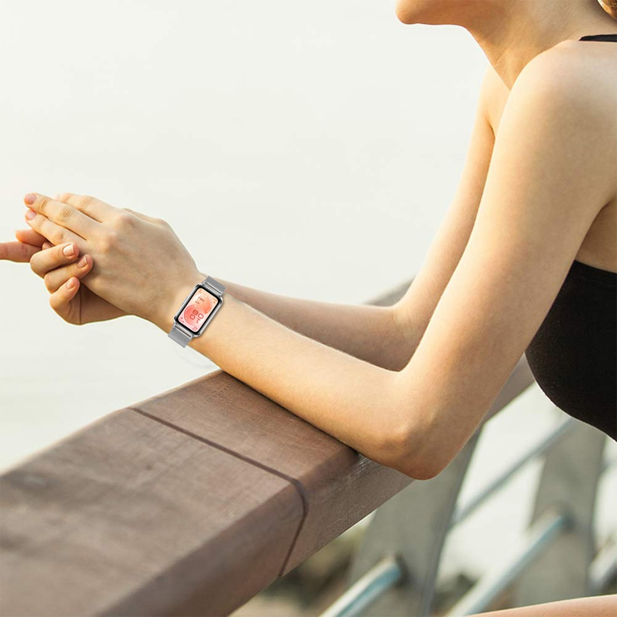 Eine Frau mit silberner Smartwatch lehnt an einer Holzbrüstung.