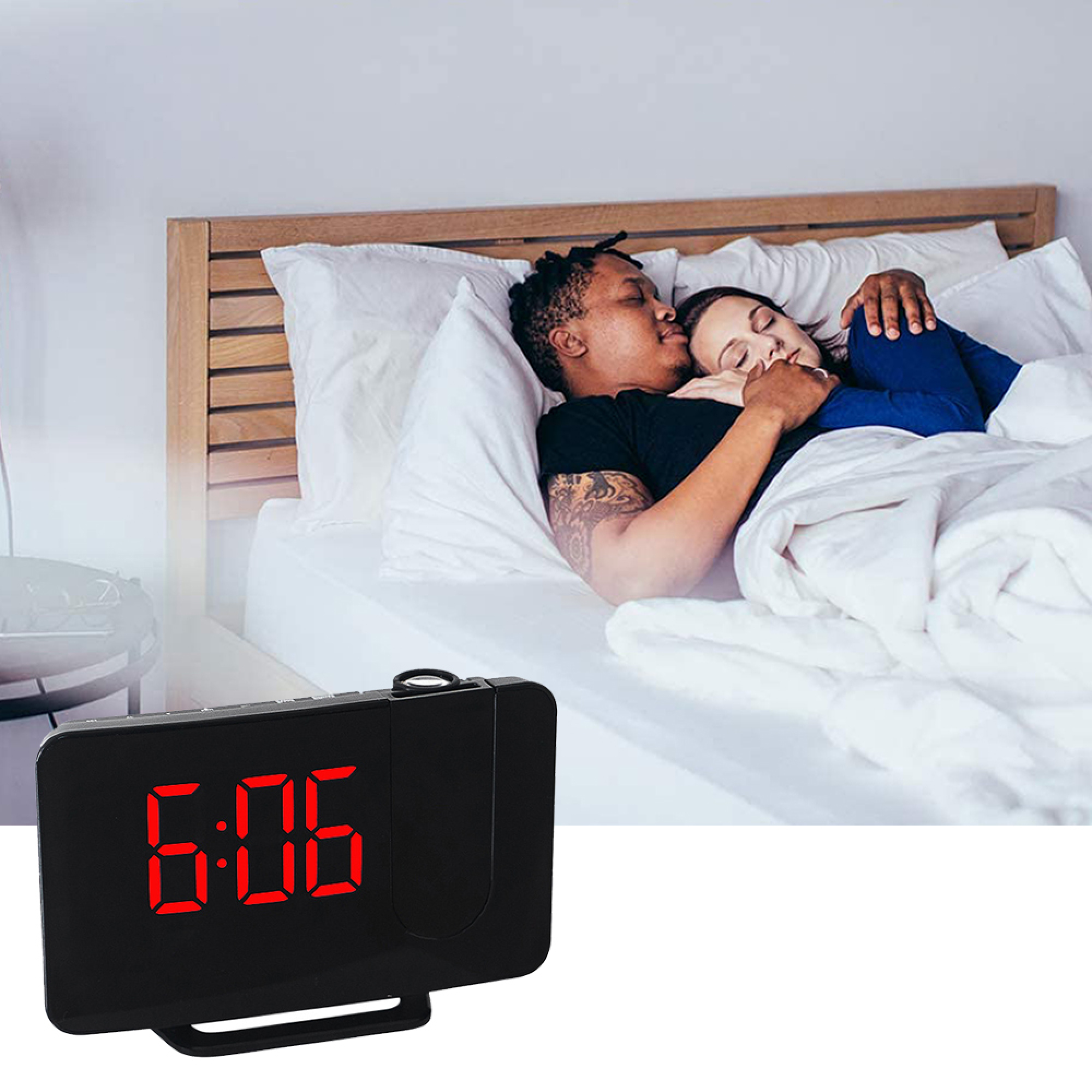 Ein Mann küsst eine schlafende Frau im Bett. Ein Projektionswecker zeigt 6:06.