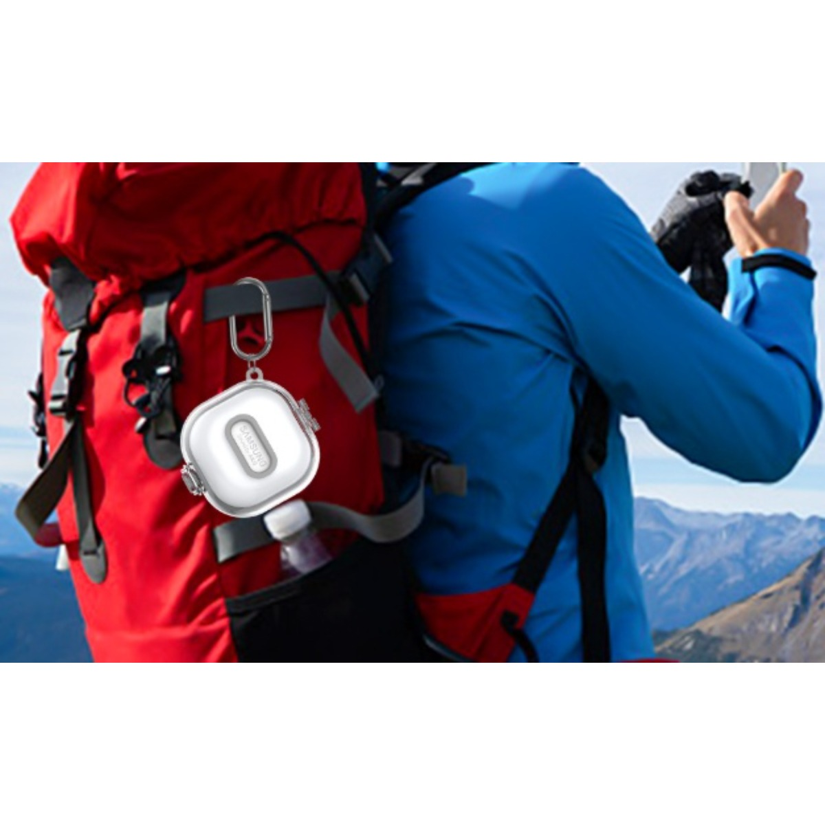 Persona in giacca blu con zaino rosso, custodia bianca su moschettone, montagne.
