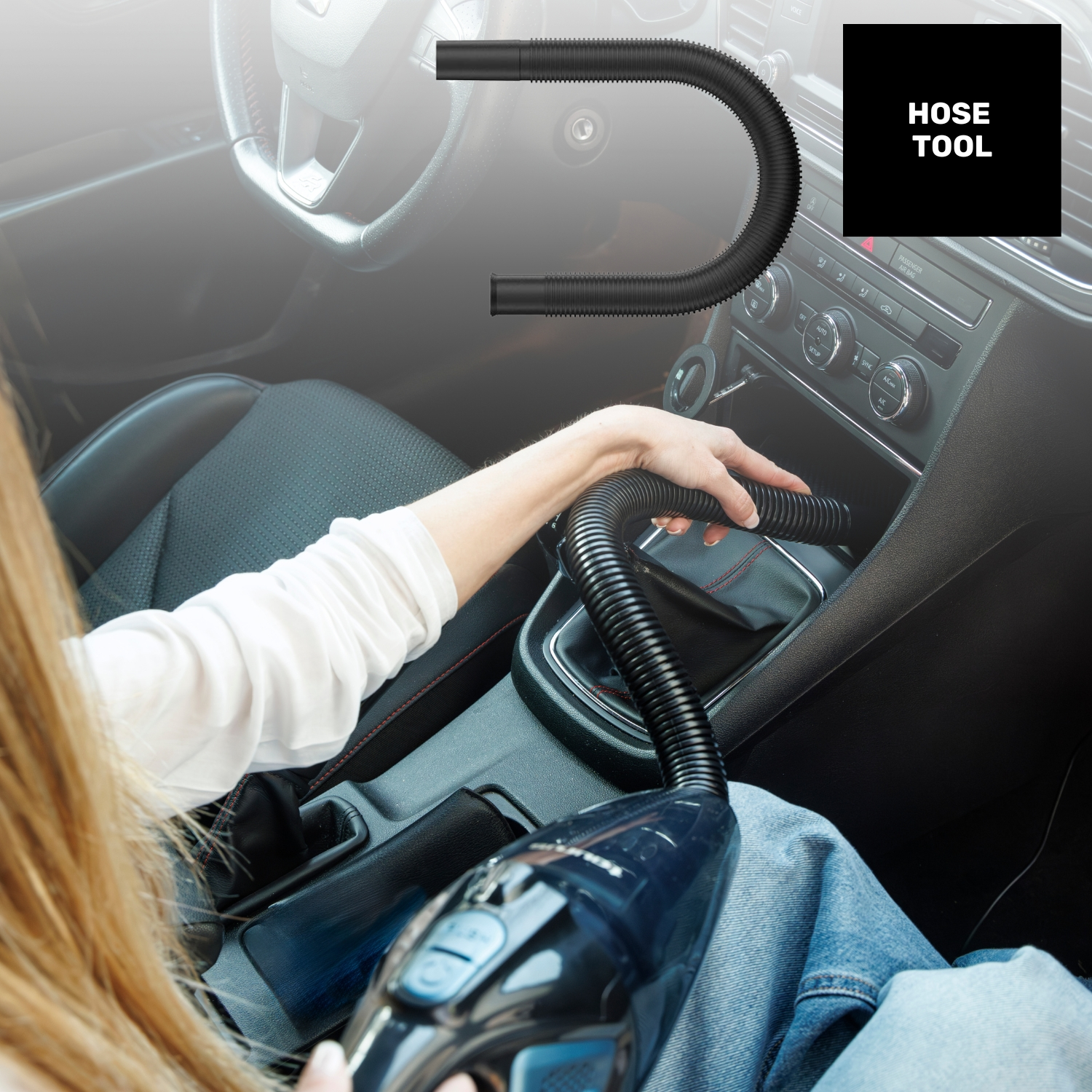 Una mujer limpia el interior de un coche con un accesorio de manguera flexible.