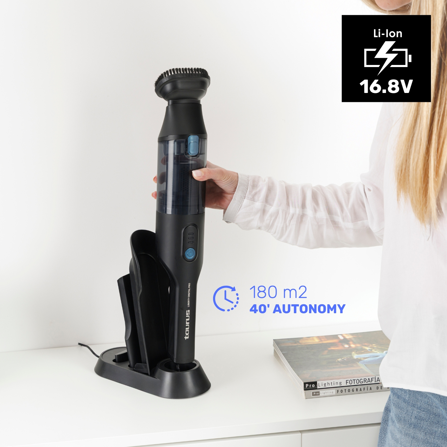 Una aspiradora negra de mano con cepillo está en su base de carga. Li-Ion 16.8V.