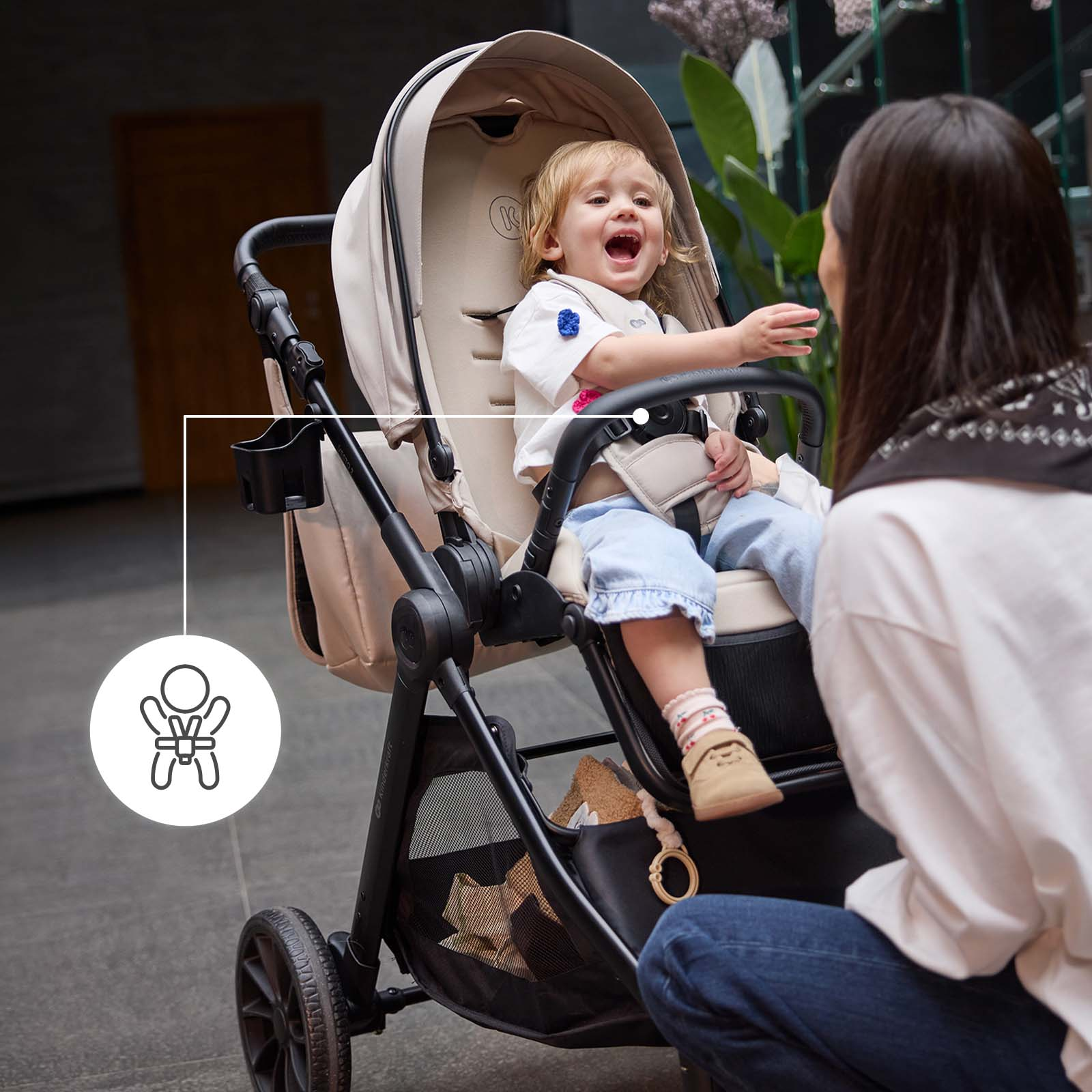 Ein Baby sitzt in einem Kinderwagen, während eine Frau davor kniet.