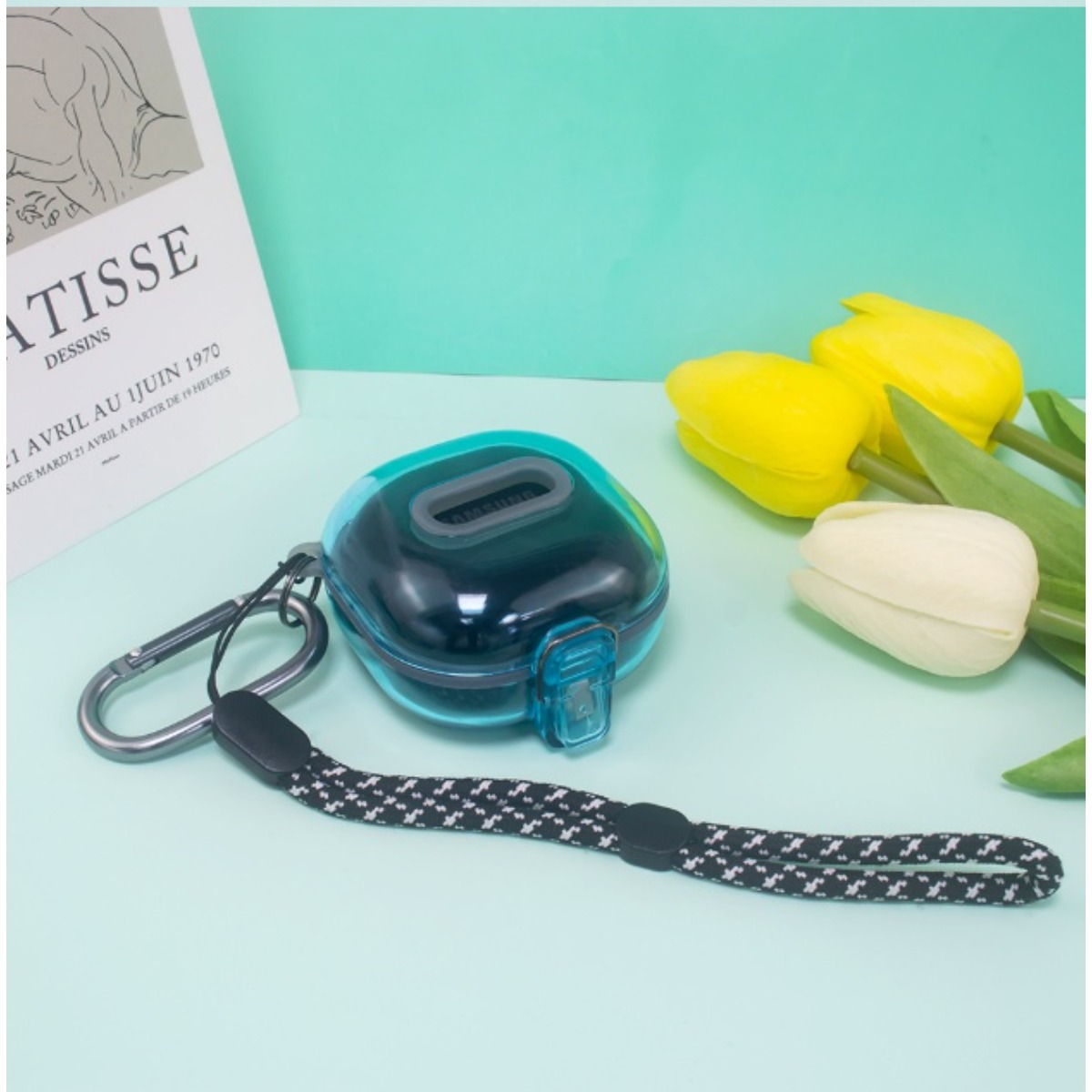 Eine blaue Hülle mit Lanyard liegt neben Tulpen und einer Matisse-Zeichnung.