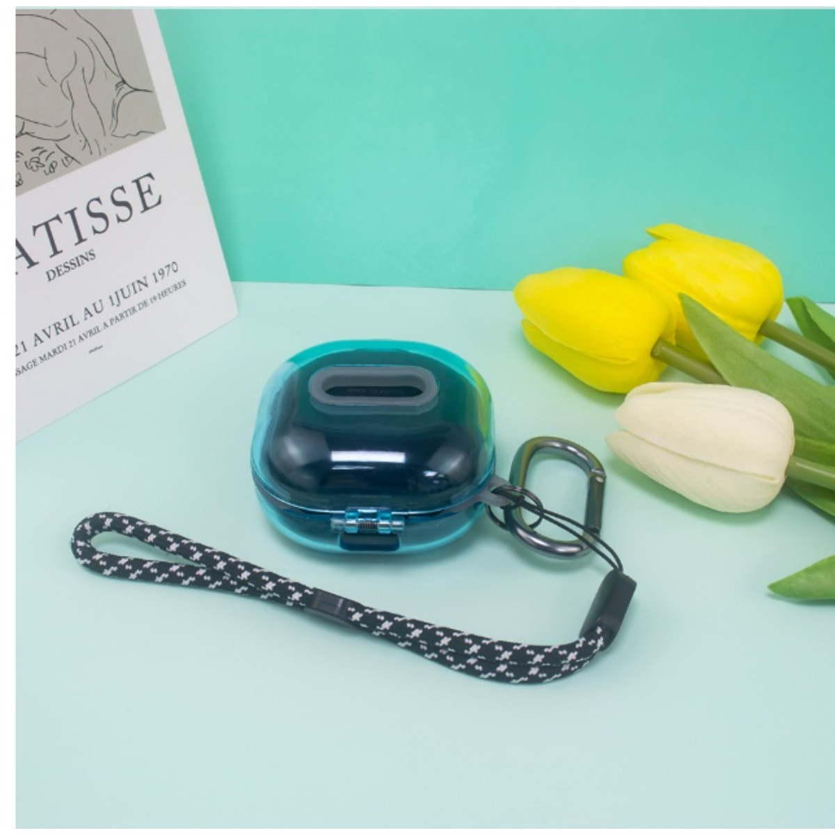 Ein blauer Kopfhörer-Case mit Lanyard und Blumen auf hellblauem Hintergrund.