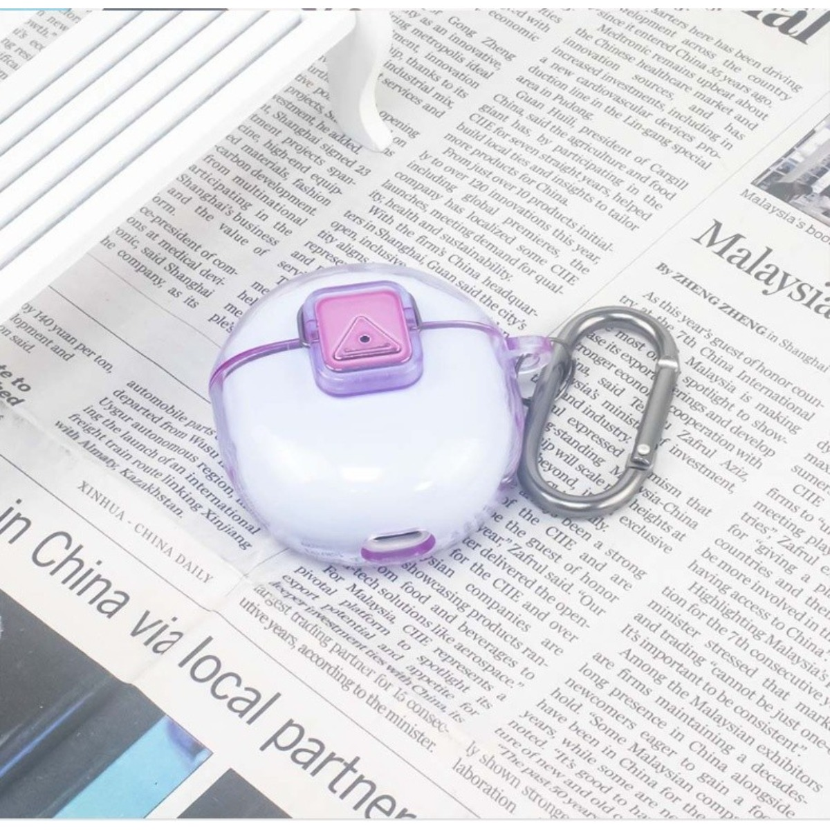 Custodia bianca per auricolari con accenti viola su un giornale.