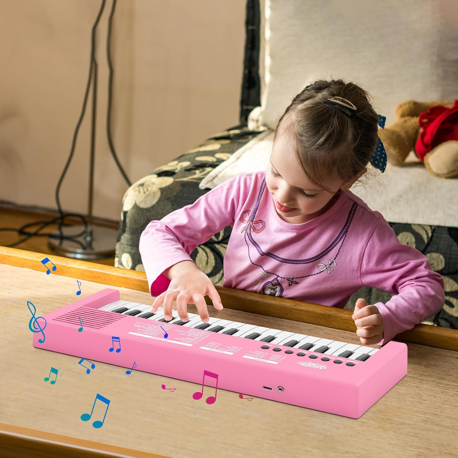 Ein kleines Mädchen spielt auf einem rosa Keyboard, bunte Noten schweben umher.