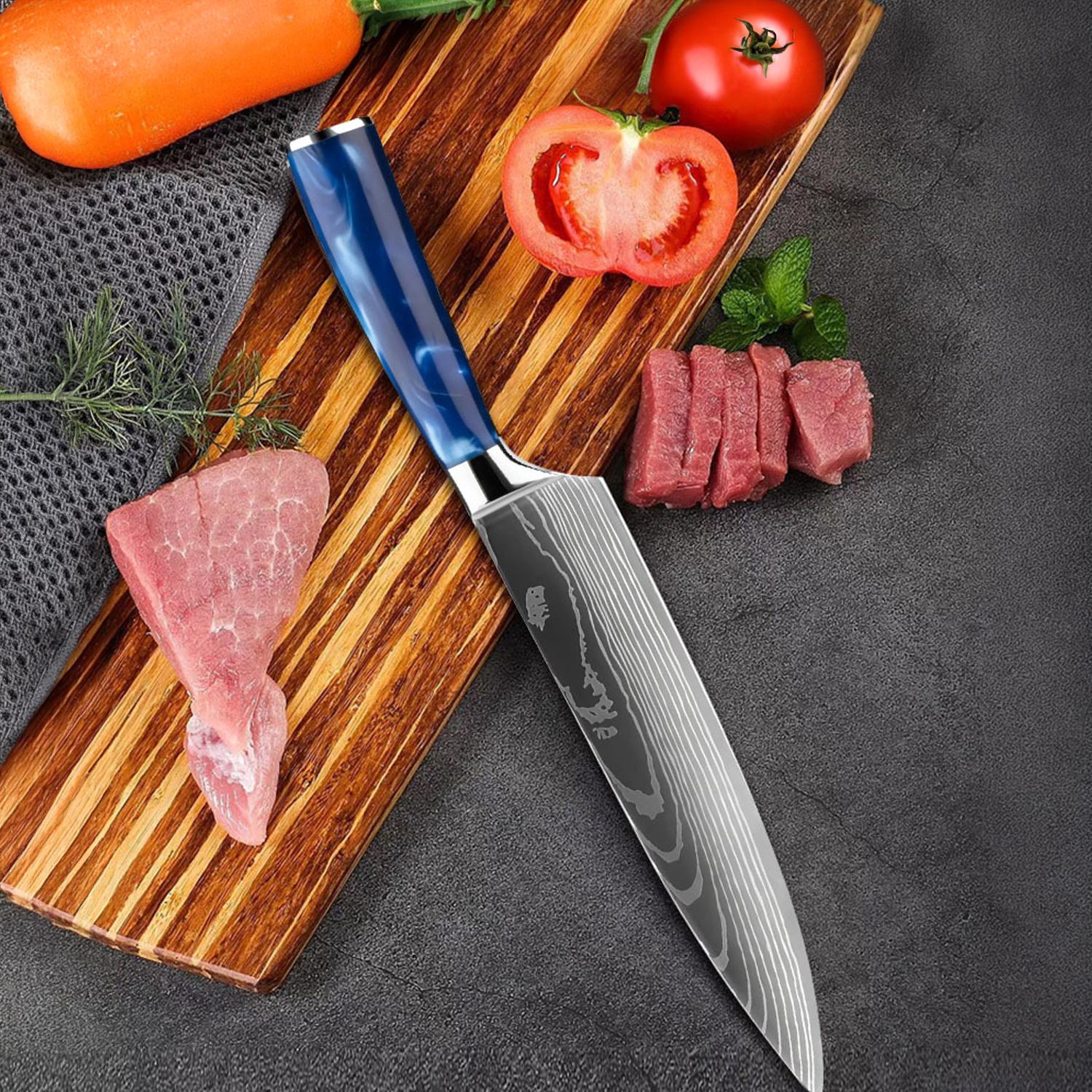 Un cuchillo con mango azul descansa sobre tabla de madera con carne cruda, zanahorias, tomates y menta.