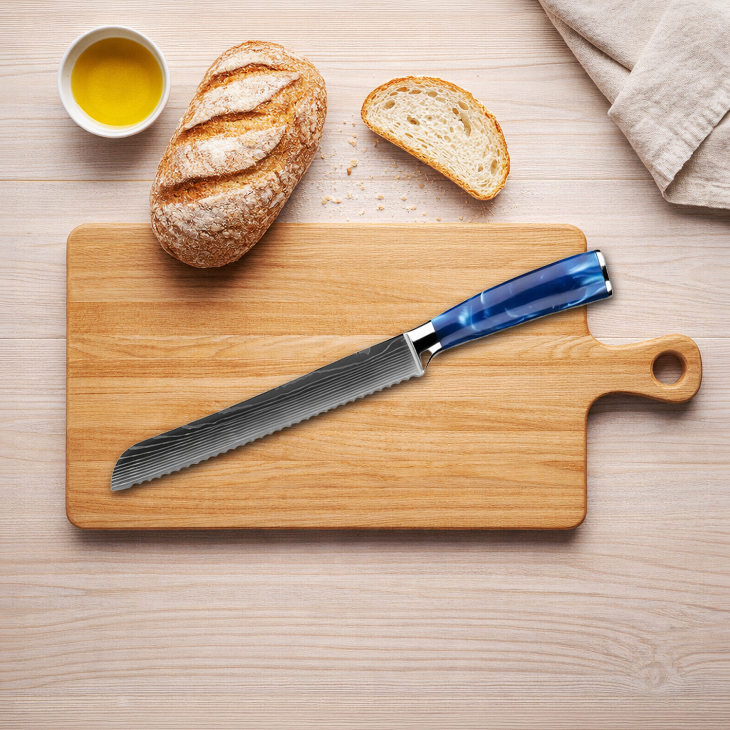 Un cuchillo para pan con mango azul yace sobre una tabla de madera junto a pan y aceite.