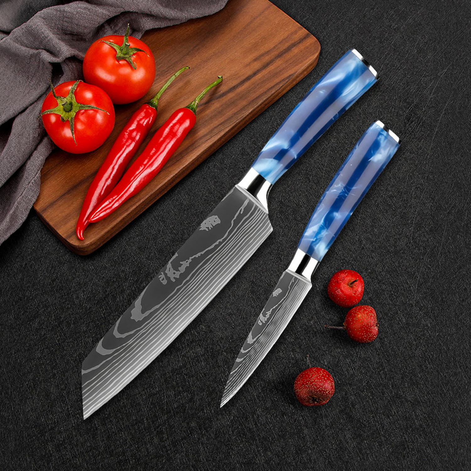 Dos cuchillos de Damasco con mangos azules junto a tomates, chiles y bayas rojas.