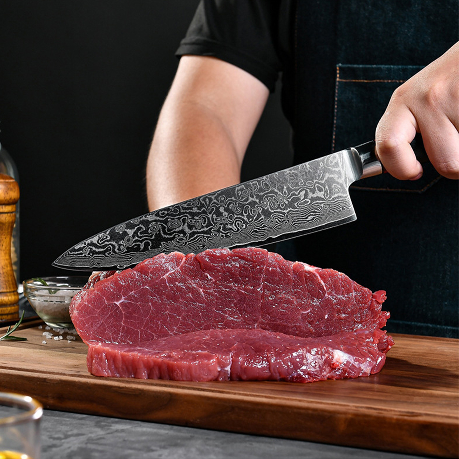 Una persona corta un trozo de carne de res cruda con un cuchillo de Damasco en una tabla.