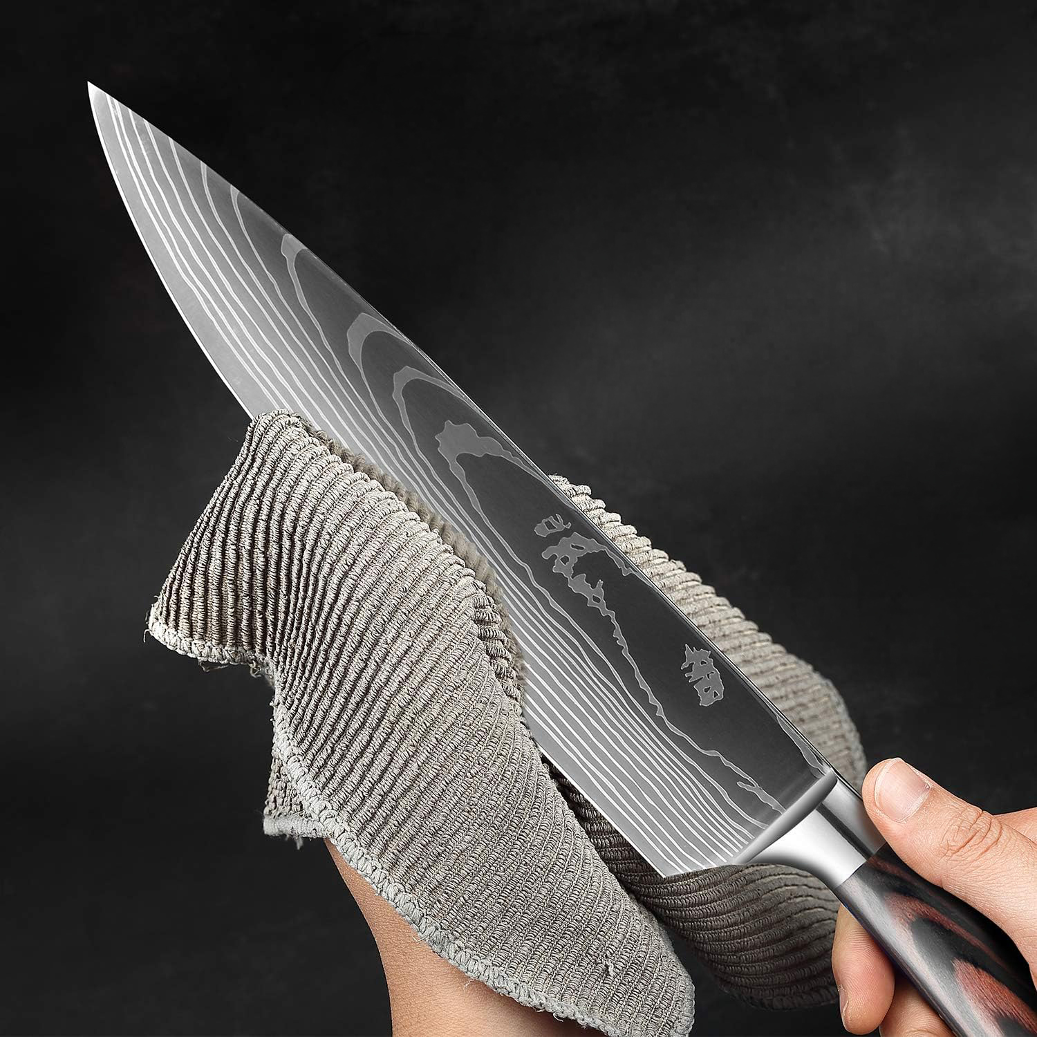 Una mano limpia un cuchillo de cocina Damasco con un paño gris.
