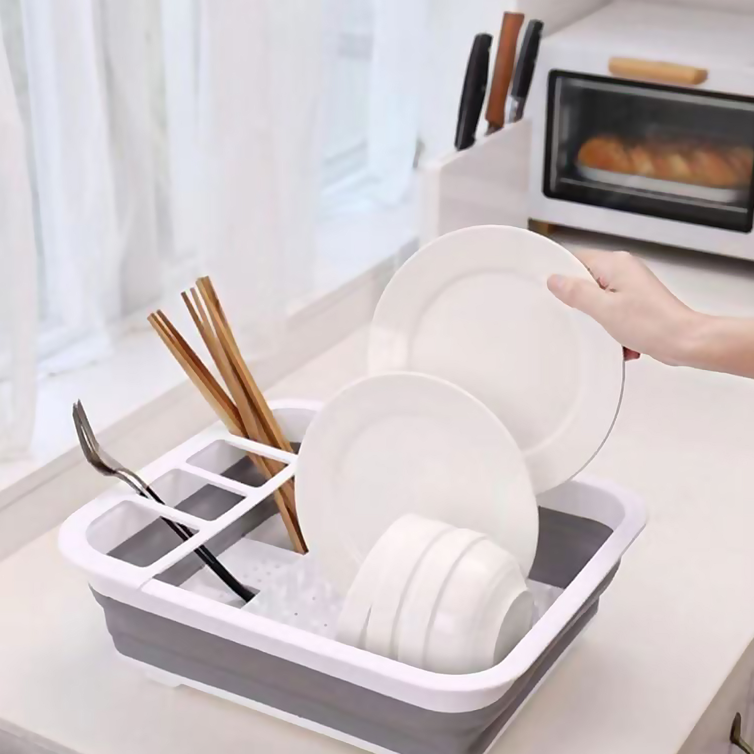 Escurridor de platos gris con platos, tazas, palillos y un tenedor.
