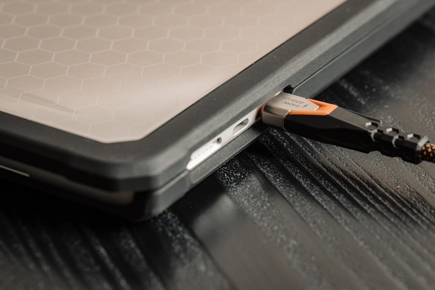 Kabel USB-C z pomarańczowymi akcentami jest podłączony do portu laptopa.