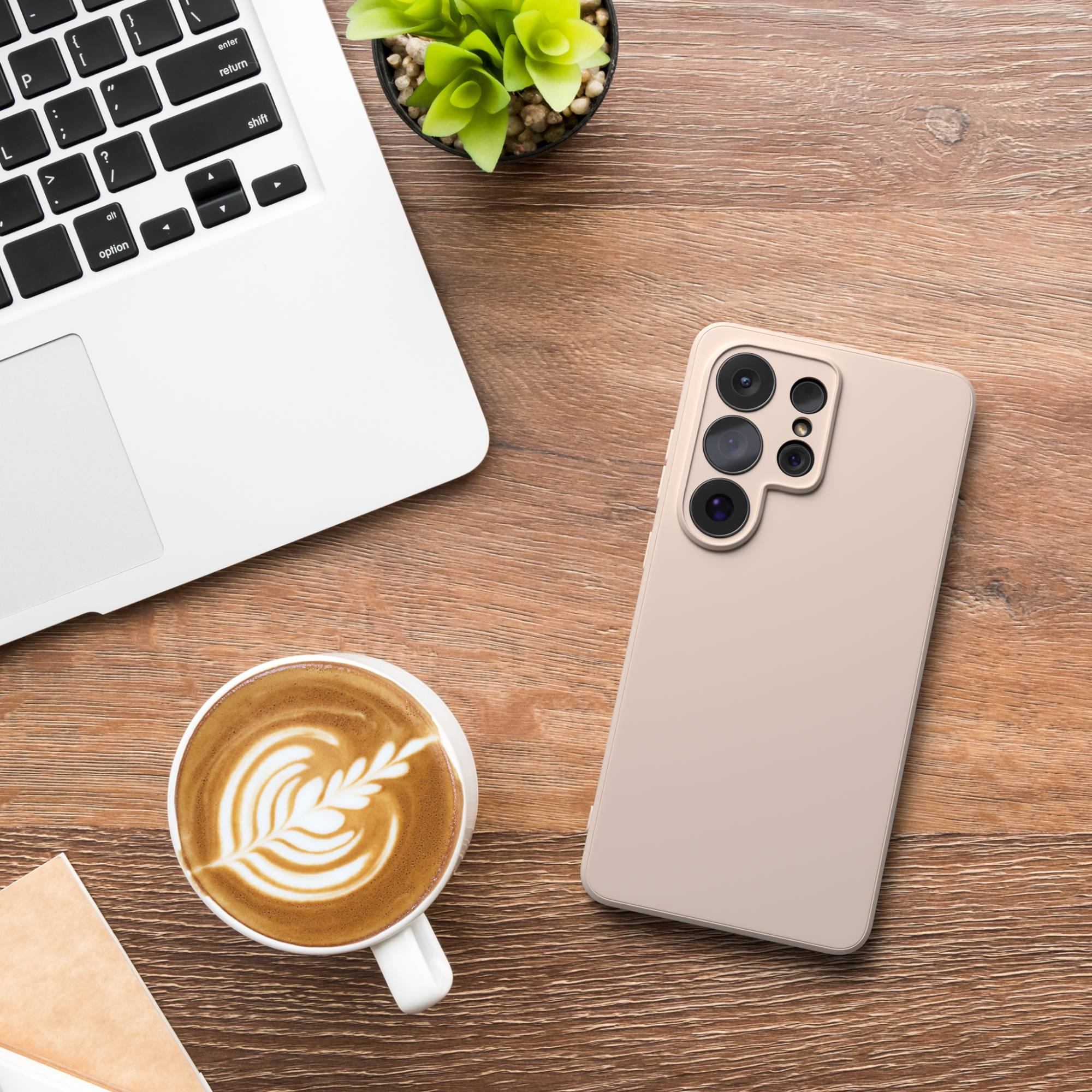 Ein Laptop, ein Smartphone, eine Kaffeetasse und eine Pflanze auf einem Holztisch.