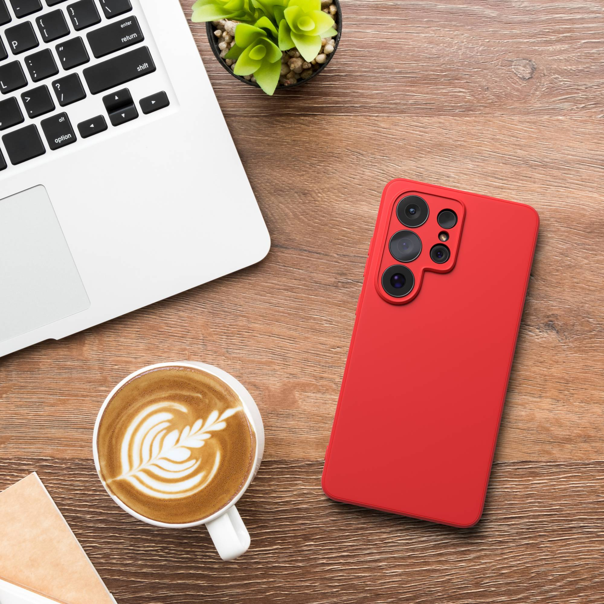 Rotes Smartphone, Laptop, Kaffeetasse und Pflanze auf Holztisch.
