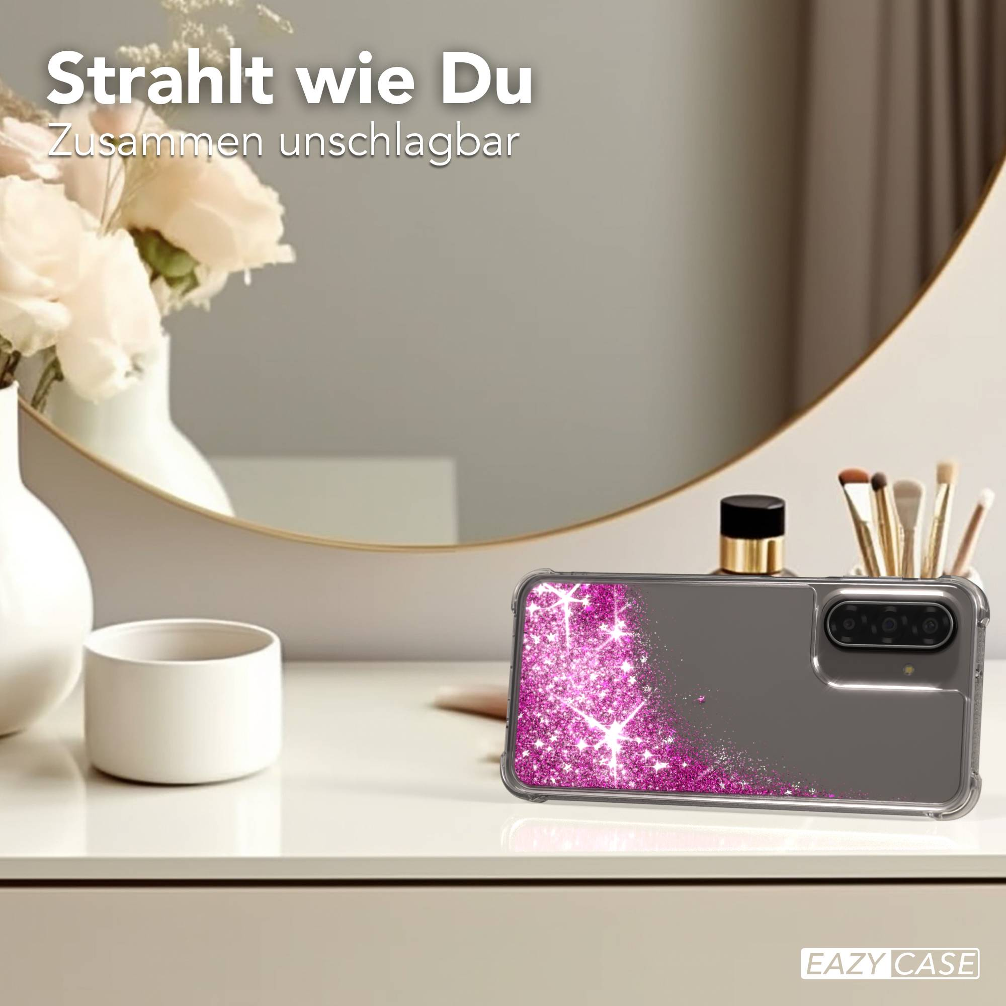 Ein Handyhülle mit Glitzer-Design liegt auf einer Kommode neben Blumen.