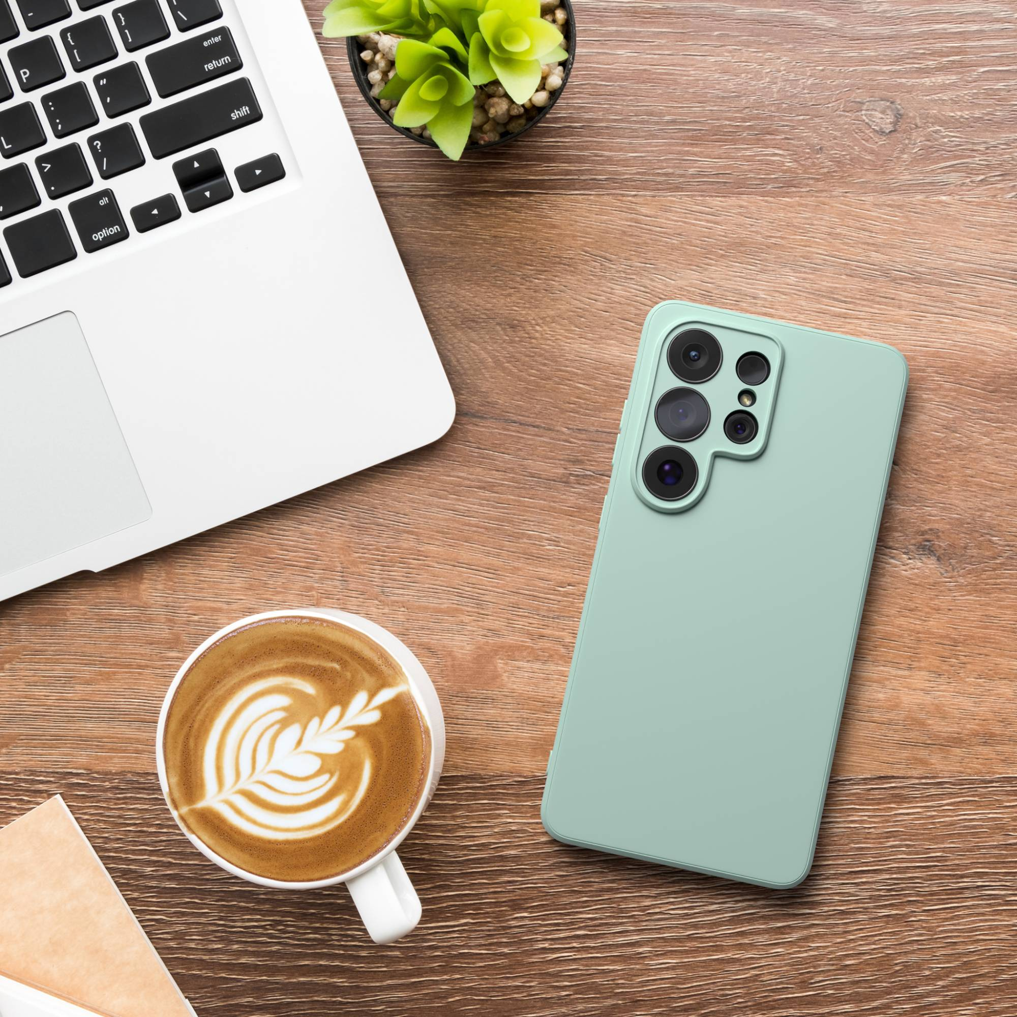 Ein Laptop, ein Handy, eine Kaffeetasse und eine Pflanze auf Holz