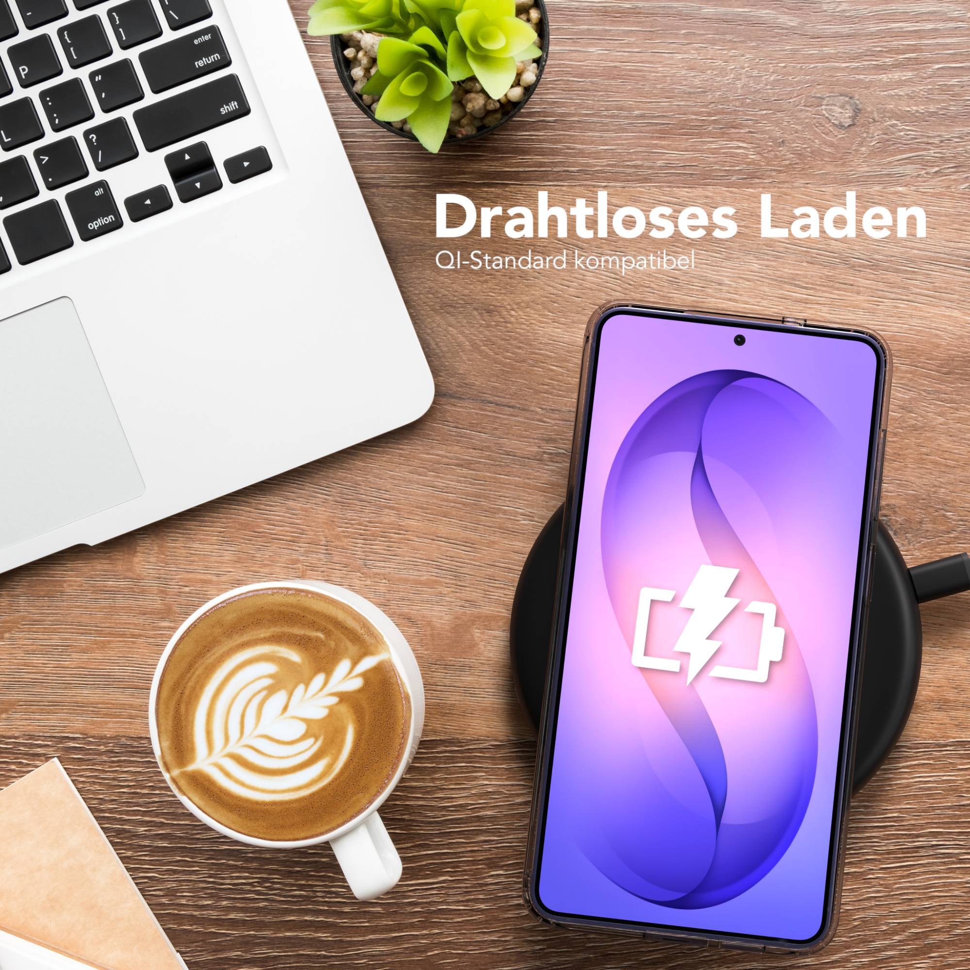 Ein Laptop, Kaffee und ein Handy auf einem Ladegerät liegen auf einem Holztisch.