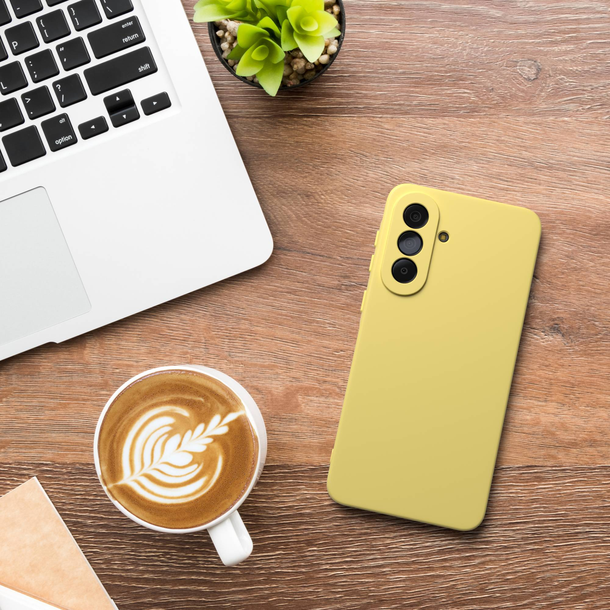 Ein gelbes Smartphone, Laptop und Latte auf einem Holztisch.