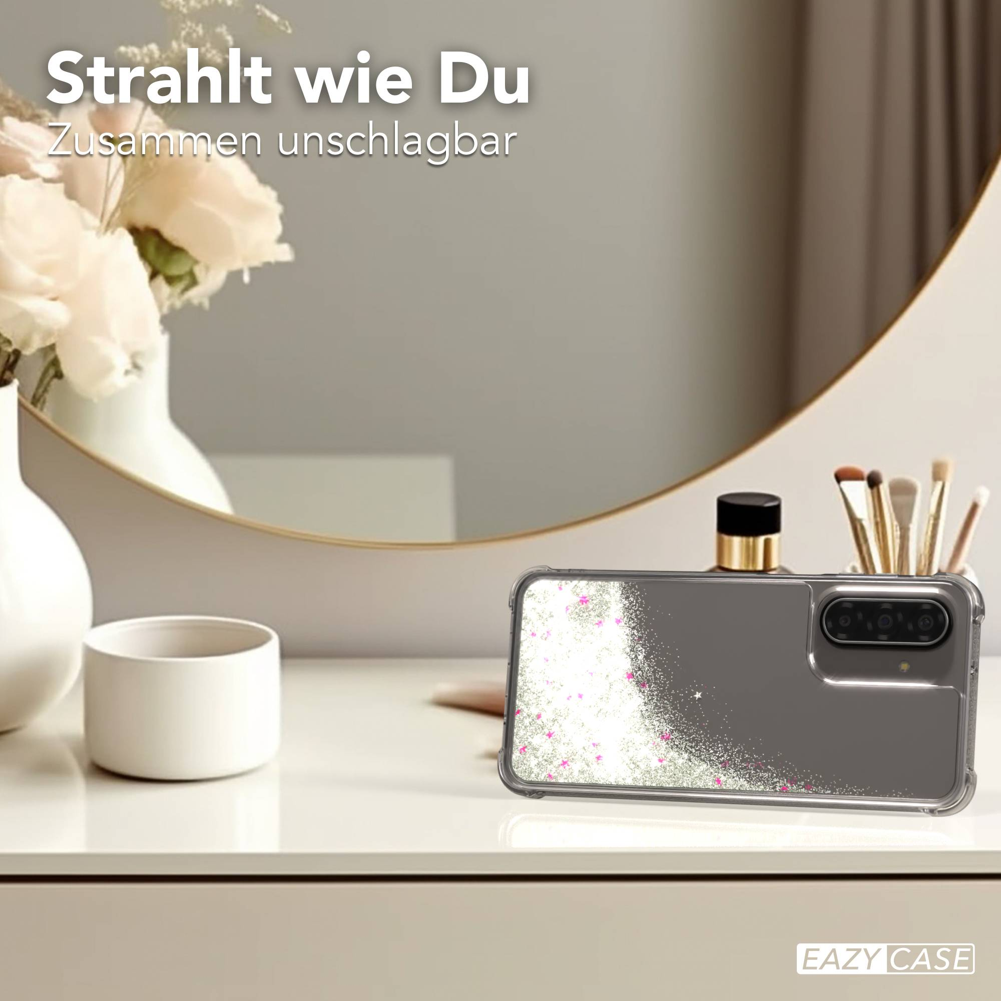 Graue Handyhülle mit Glitzer und rosa Sternen, neben Kosmetik und Blumen.