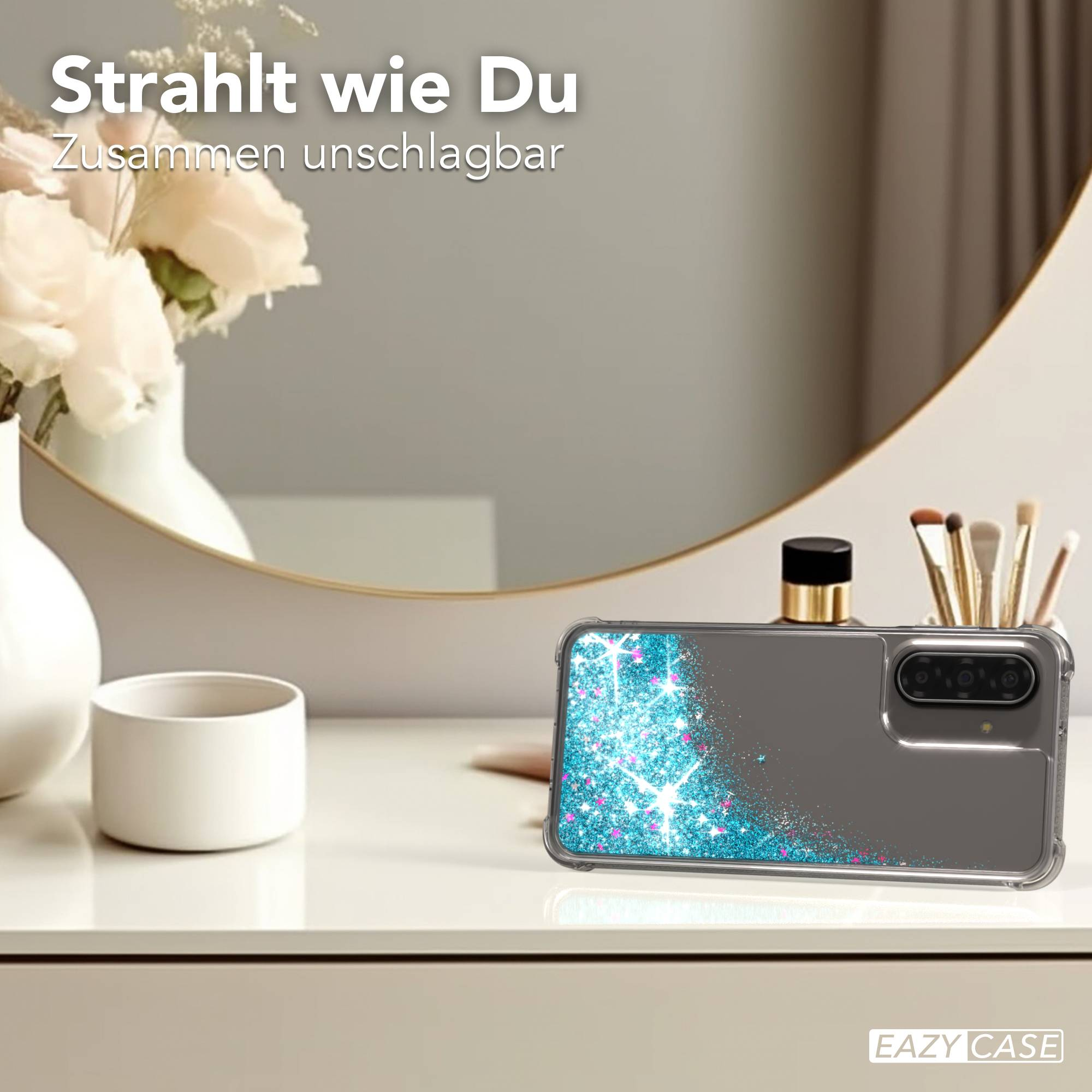 Smartphonehülle mit blauem Glitzer und rosa Tupfern, auf einem Tisch.