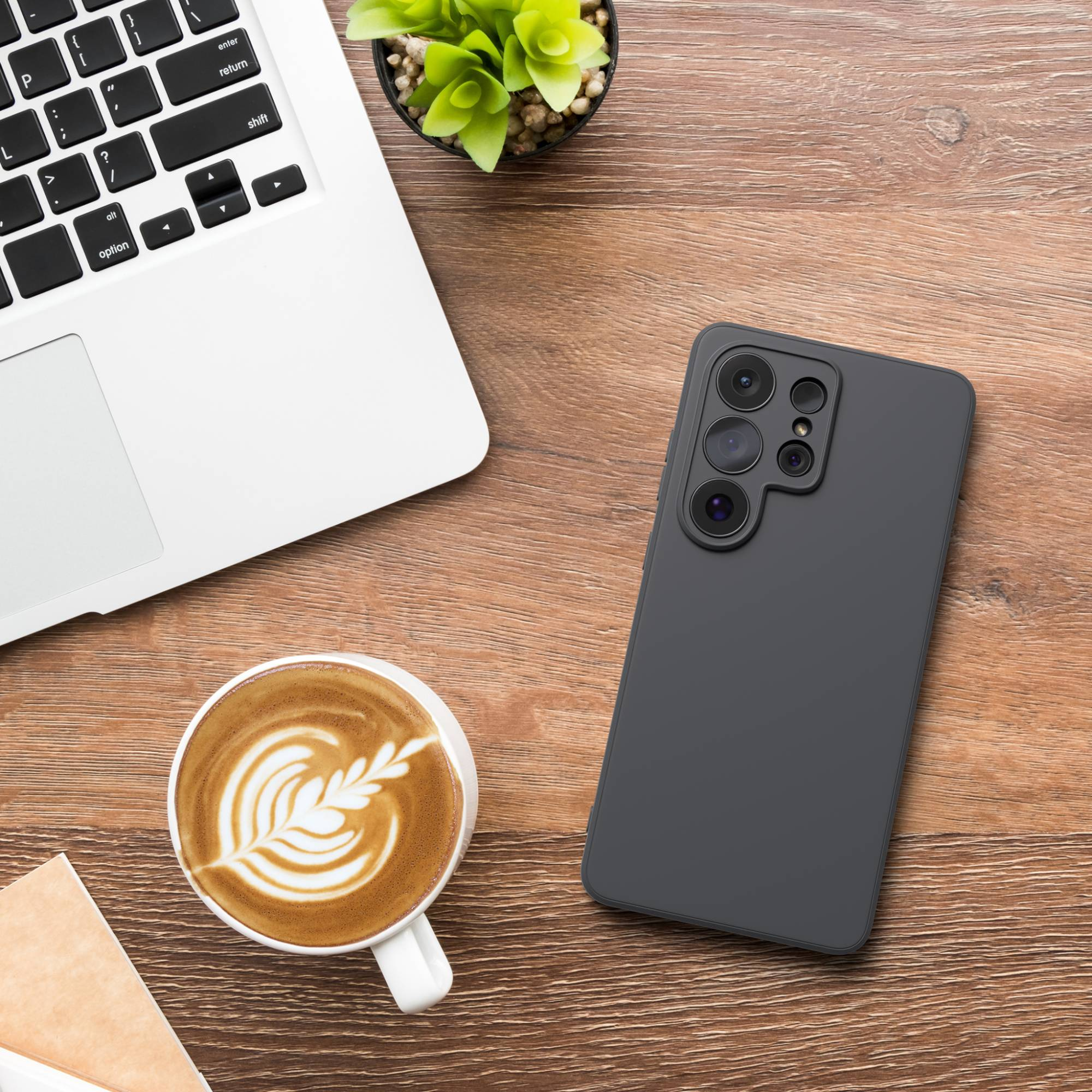 Ein Laptop, ein Smartphone und eine Kaffeetasse auf einem Holztisch.