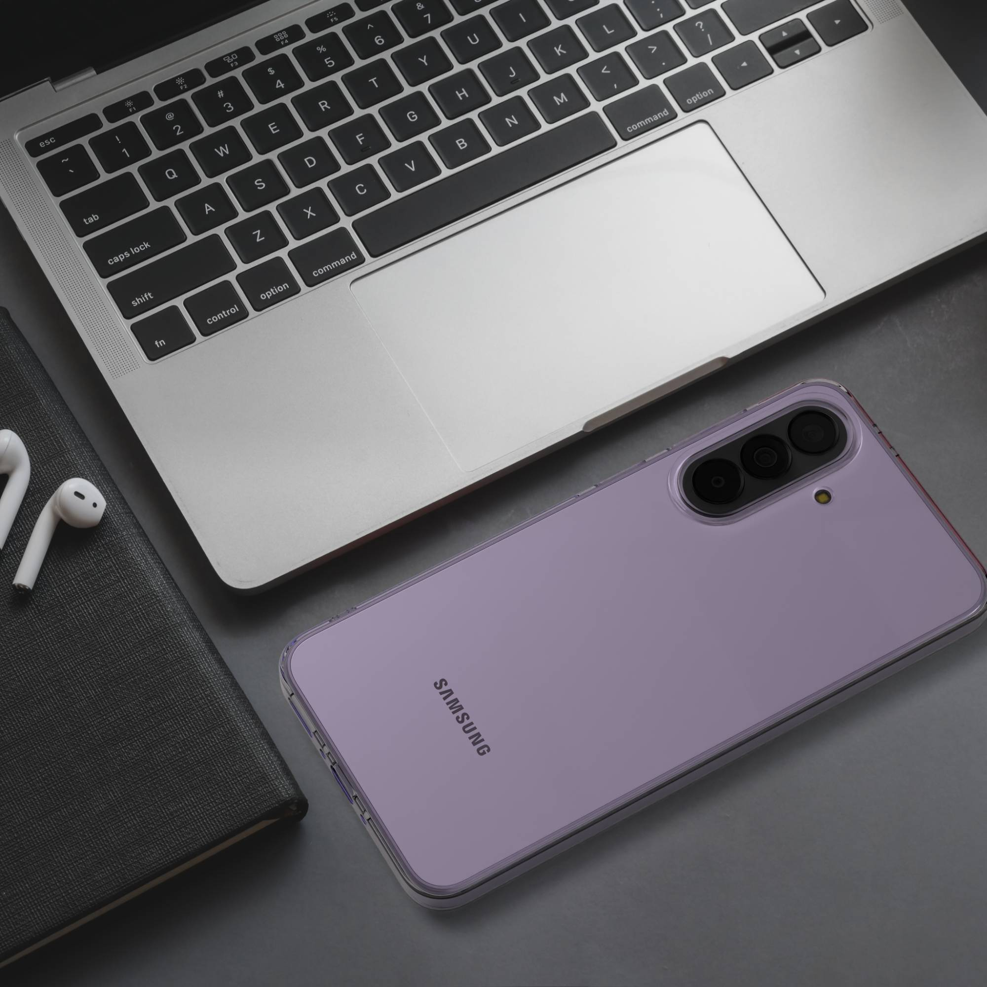 Ein lila Samsung-Handy liegt neben einem Laptop und Kopfhörern.