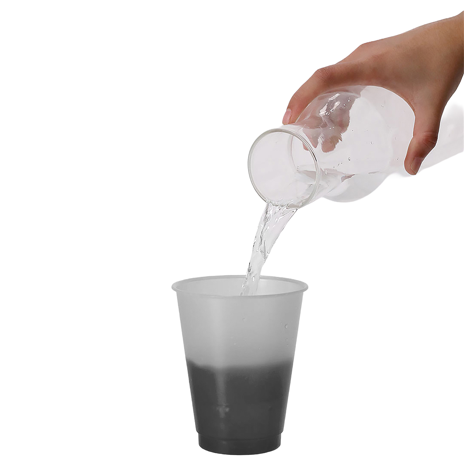 Una mano versa acqua da una caraffa di vetro in una tazza opaca.
