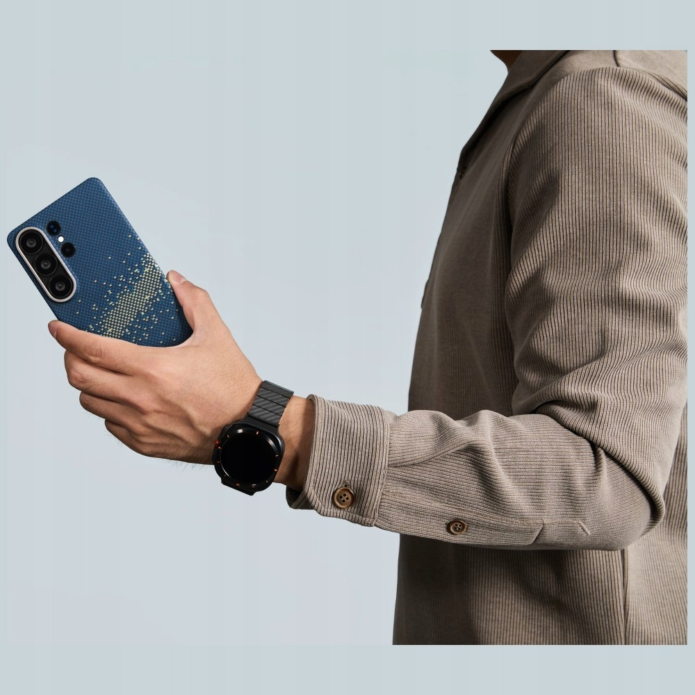 Hombre sosteniendo teléfono azul con patrón, lleva reloj y camisa.