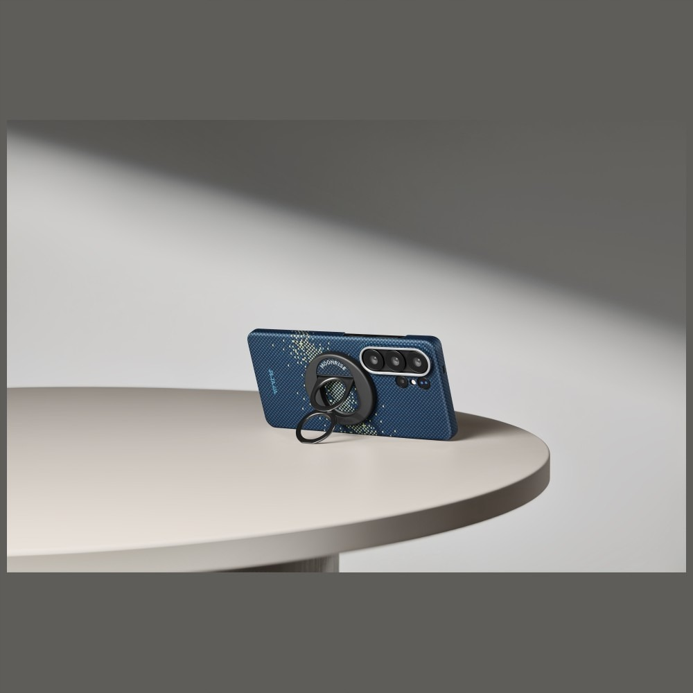 Teléfono azul oscuro con soporte de anillo en mesa clara, sombras detrás.